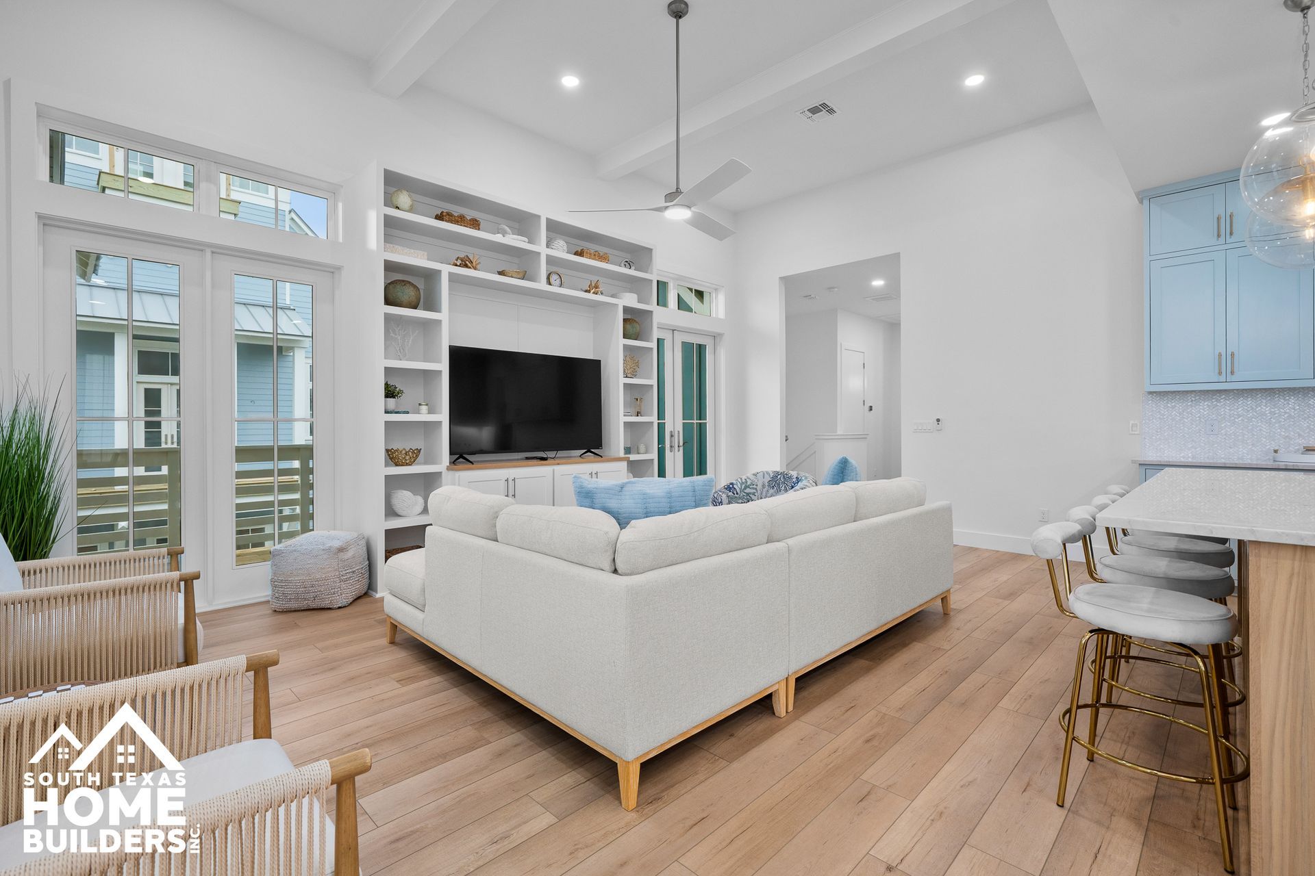 Modern living room with built-in shelves, sectional sofa, and light wood flooring.