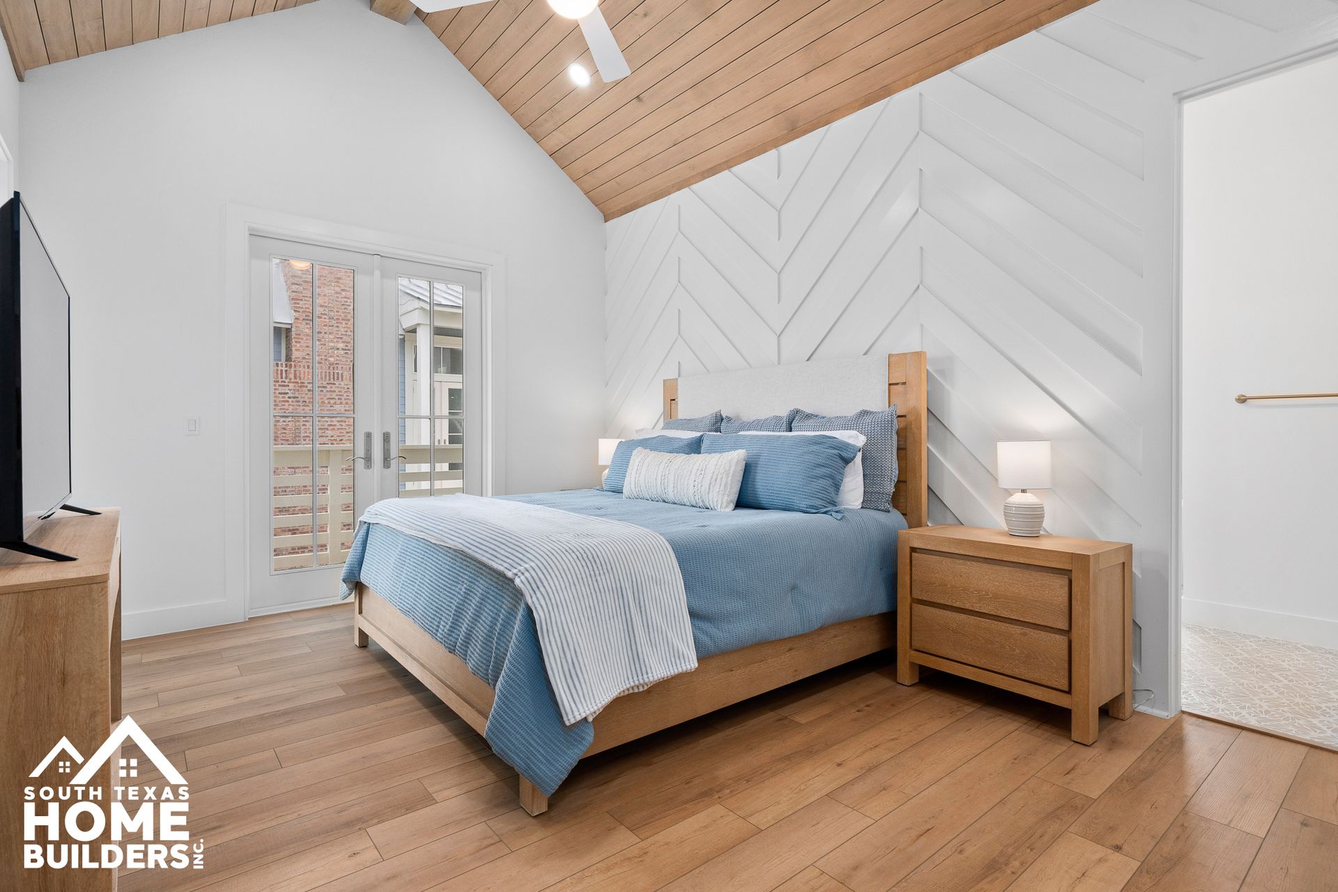 Bedroom with a wooden bed, light blue bedding, and a white and wood paneled accent wall.