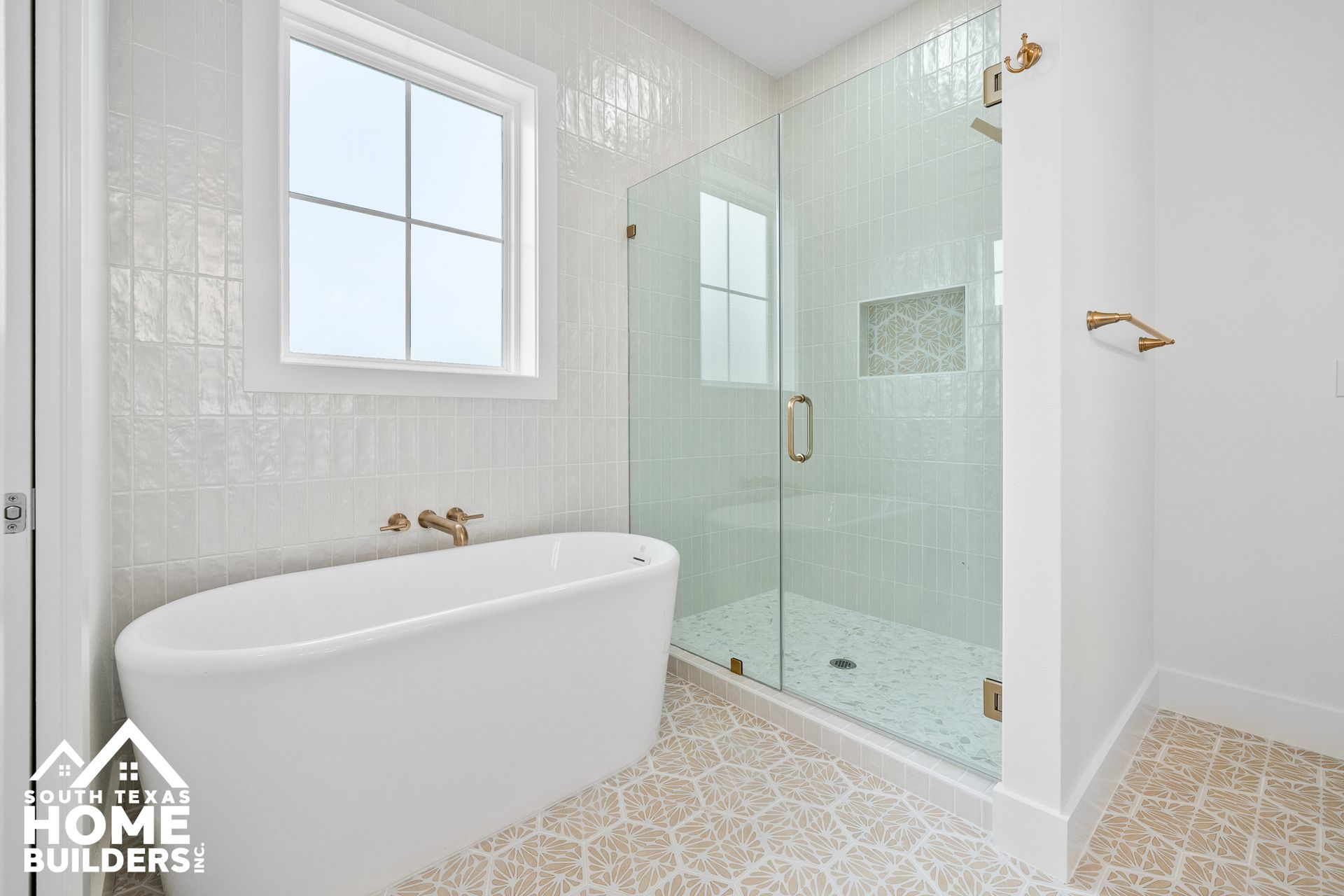 Modern white bathroom with a freestanding tub, glass shower, and patterned floor.