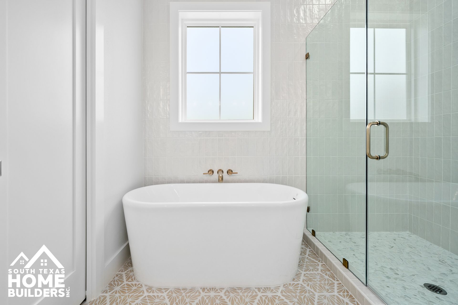 Bathroom with a white freestanding bathtub, glass shower, and window.