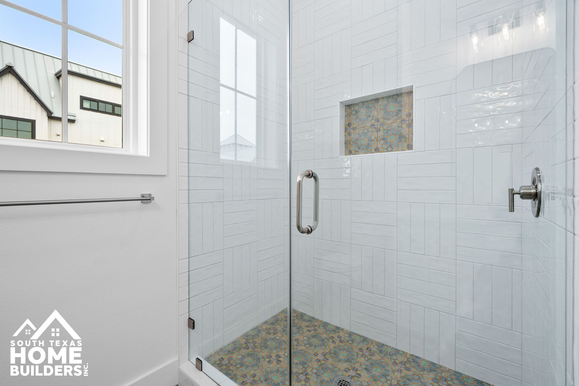 Glass shower with white subway tile, a small niche, and a window.