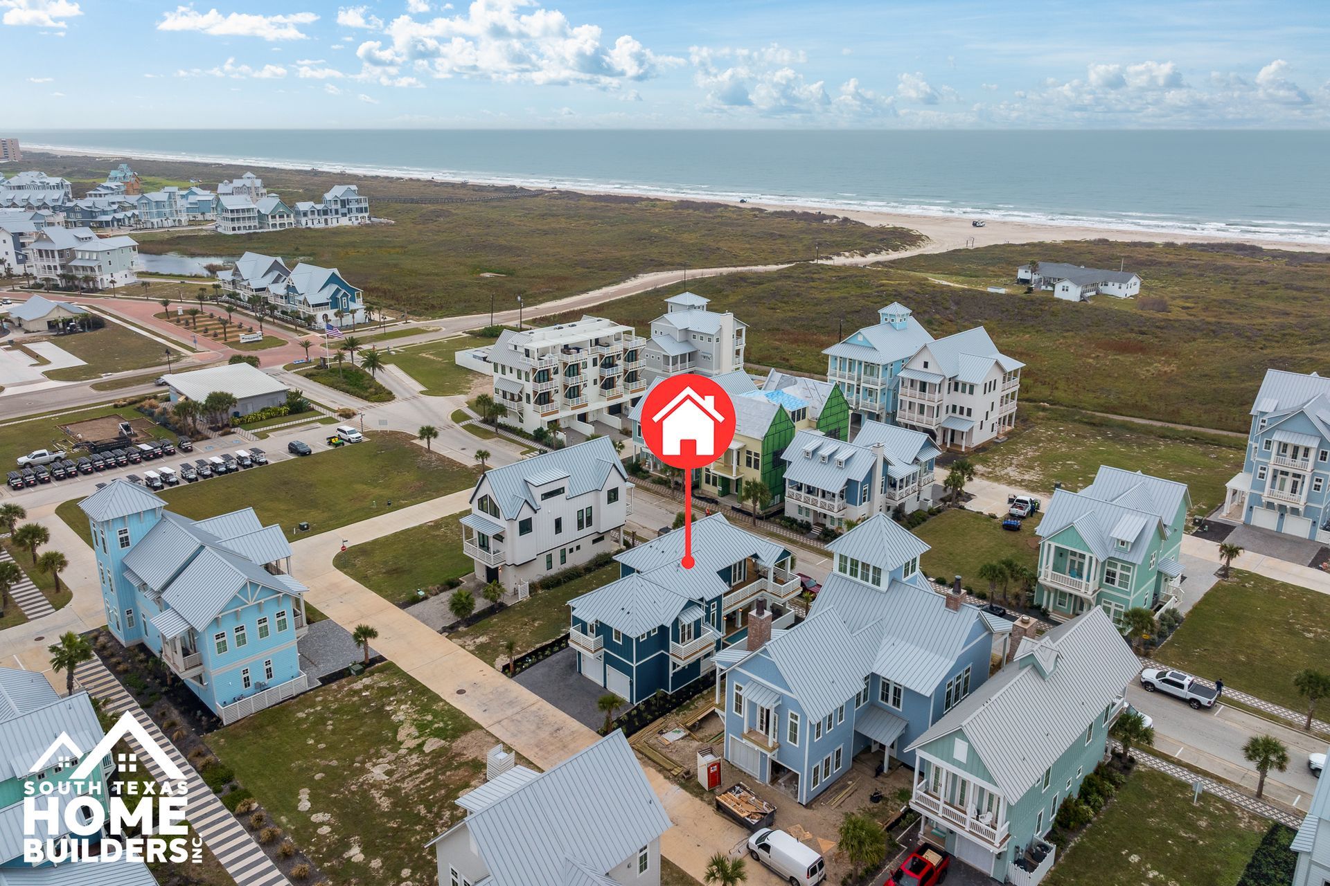 Aerial view of colorful beachfront homes near the ocean. A red house icon pinpoints a house.