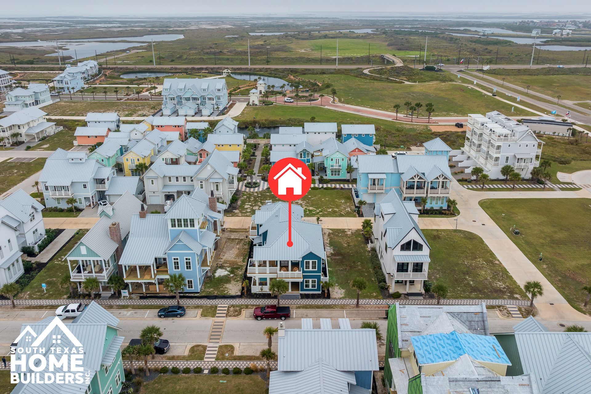 Aerial view of colorful beach houses, red house icon centered.