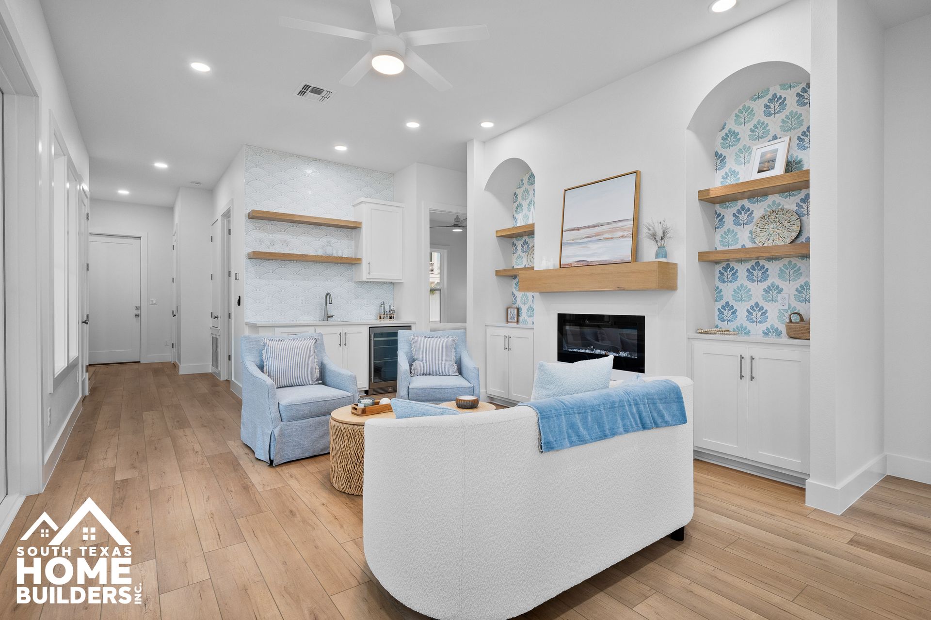 Light-filled living room with white walls, built-ins, light wood floors, and blue accents.