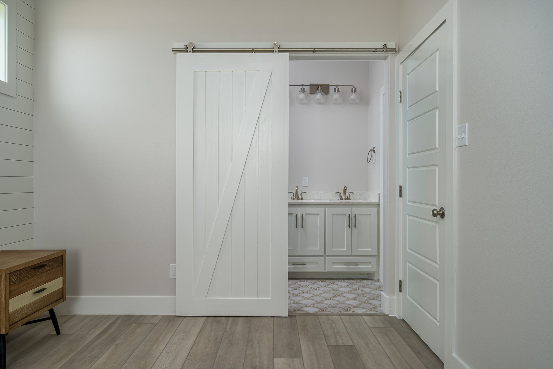A bathroom with a sliding barn door leading to it.