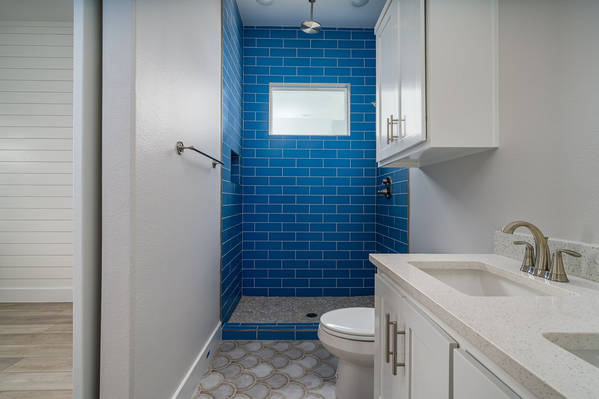 A bathroom with blue tiles and a toilet and sink