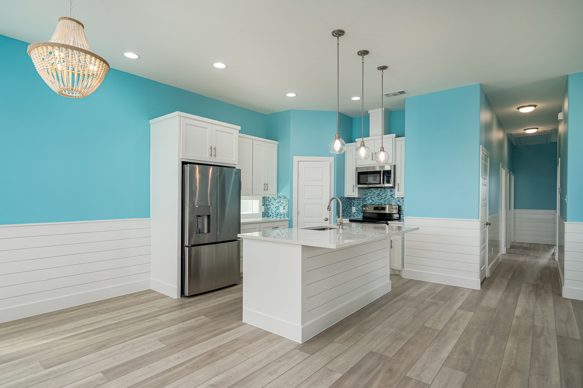 A kitchen with blue walls and white cabinets and a stainless steel refrigerator.