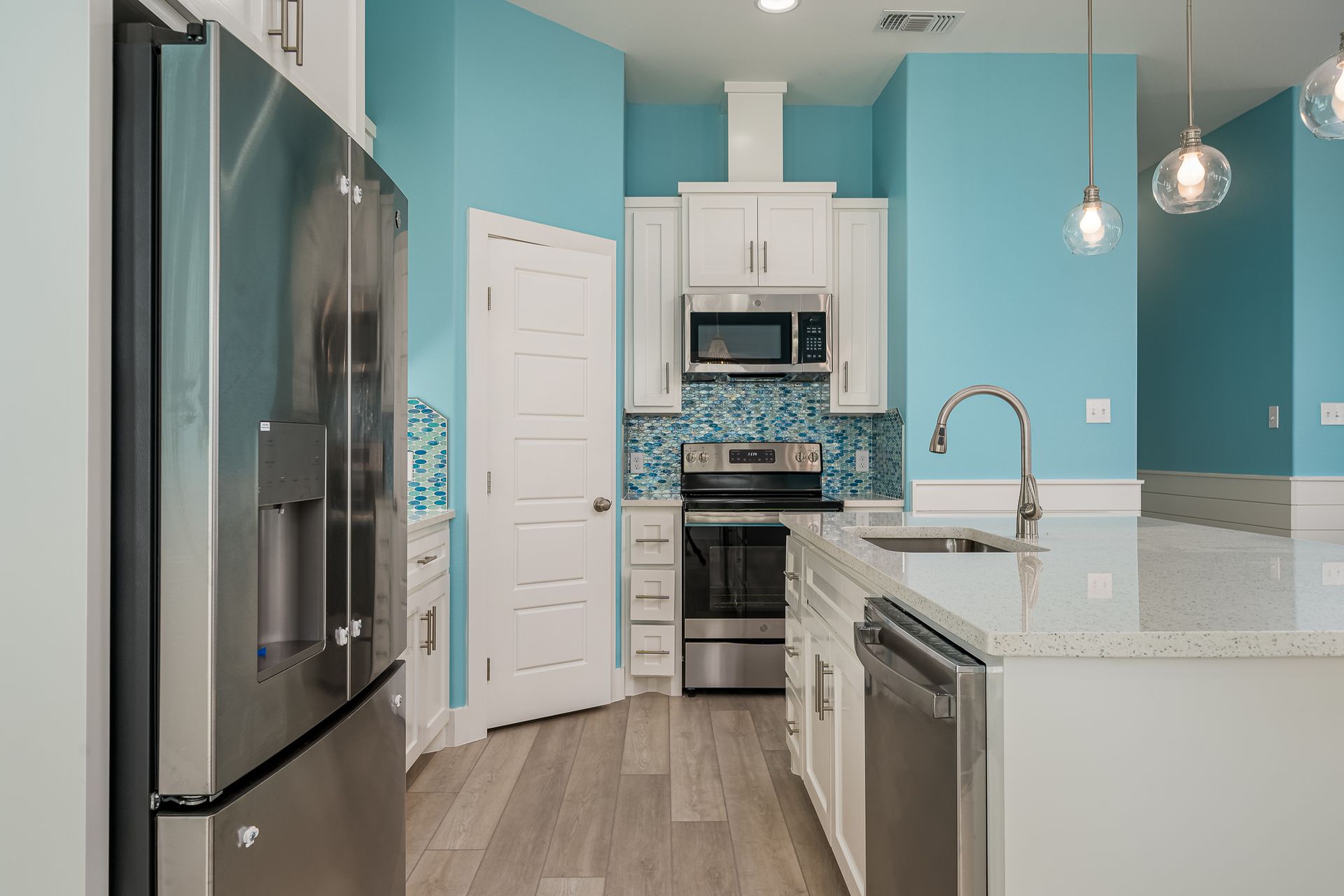 A kitchen with blue walls and white cabinets and stainless steel appliances.