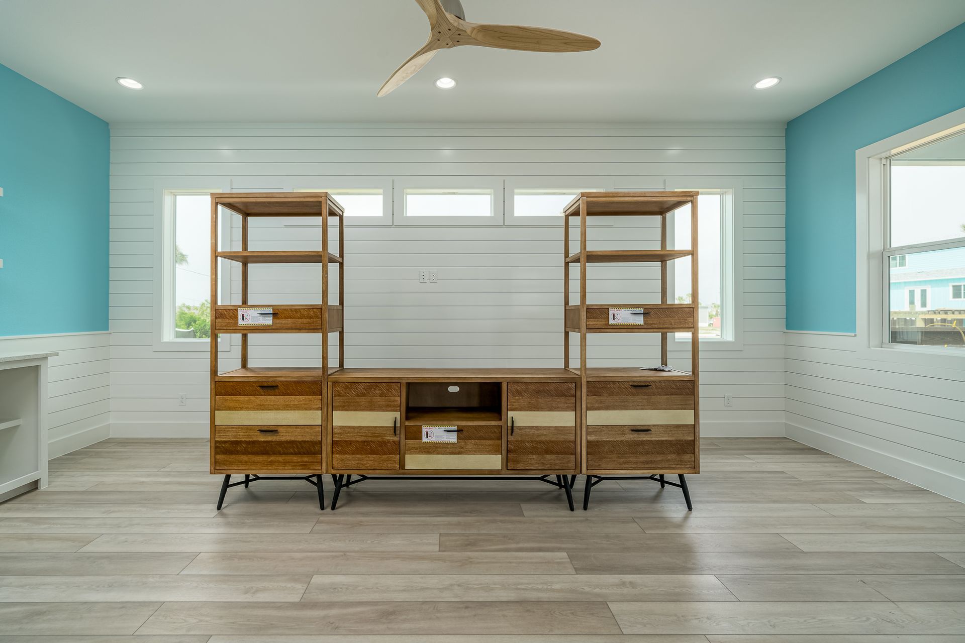 A living room with a wooden entertainment center and a ceiling fan.