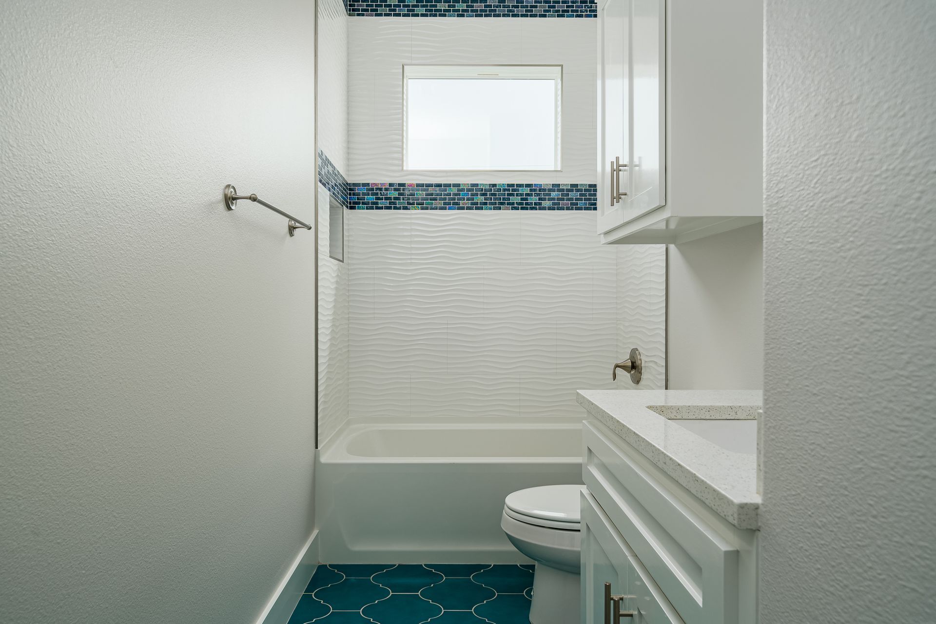 A bathroom with a tub , toilet , sink and window.