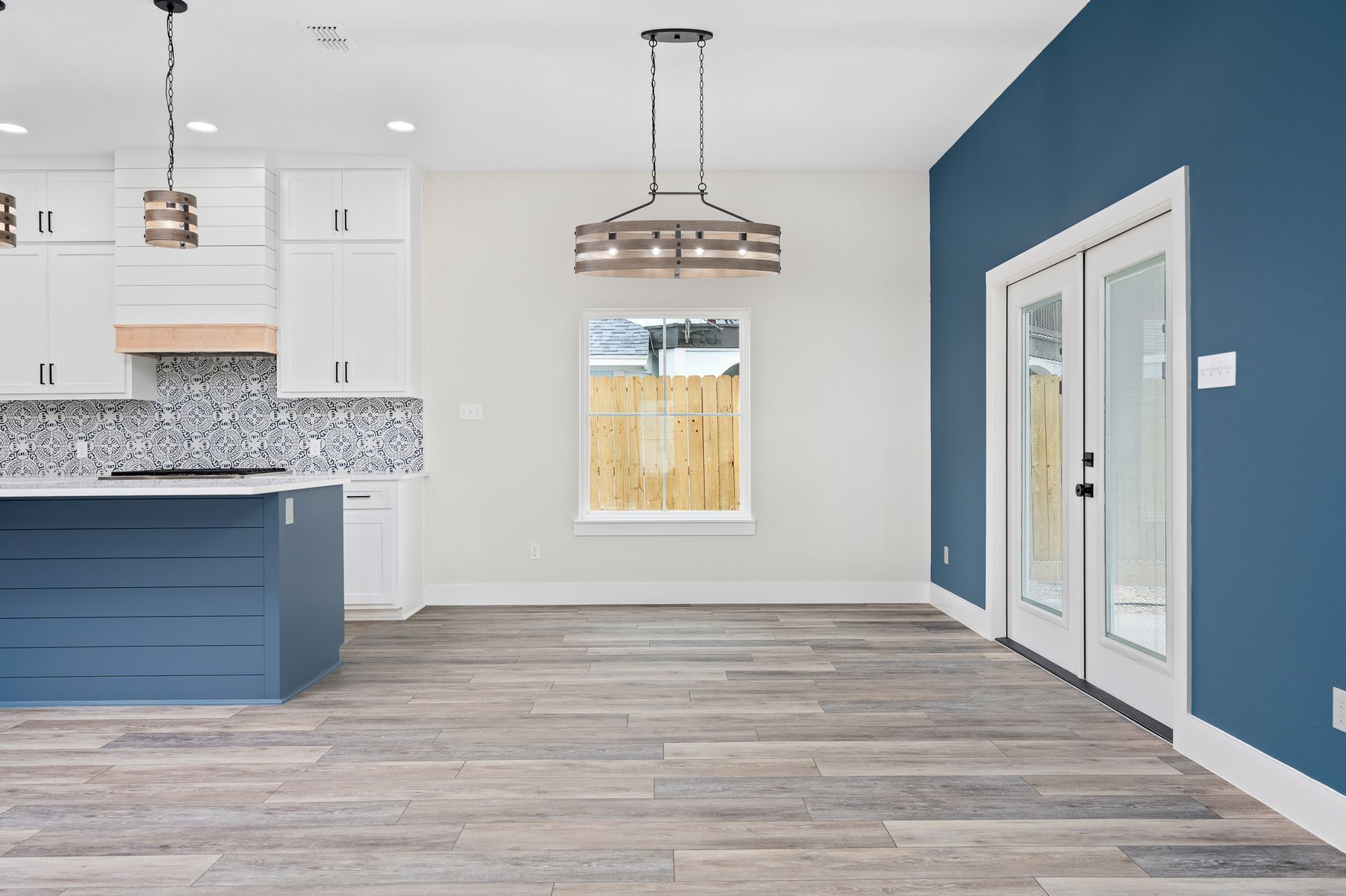 An empty kitchen with a blue island and white cabinets