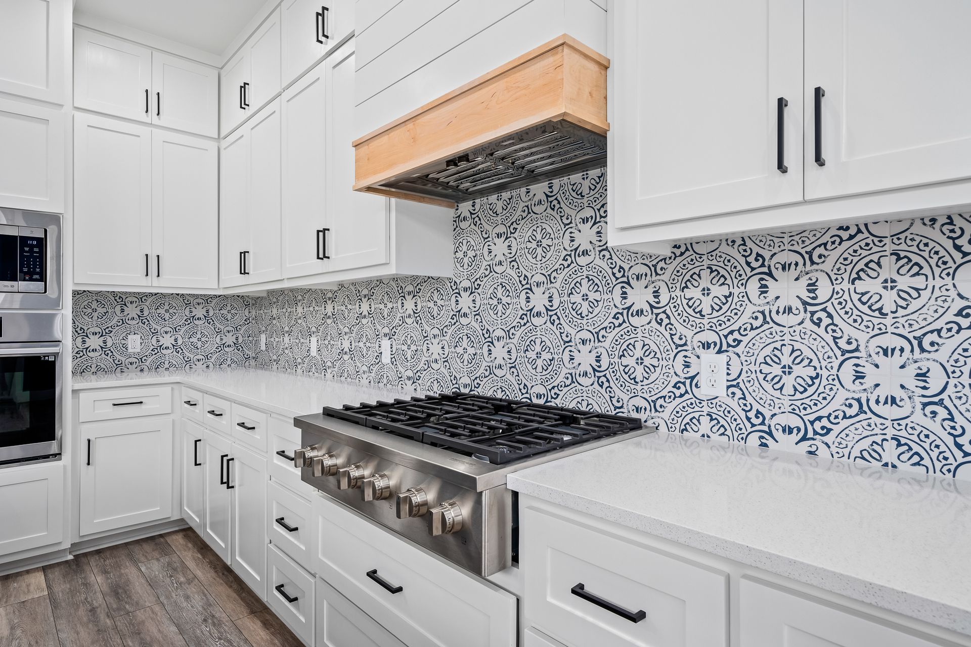 A kitchen with white cabinets and a stove top oven.