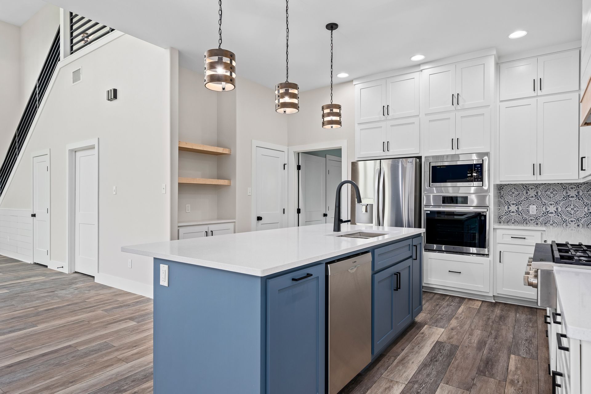 A kitchen with blue cabinets , white cabinets , stainless steel appliances and a large island.