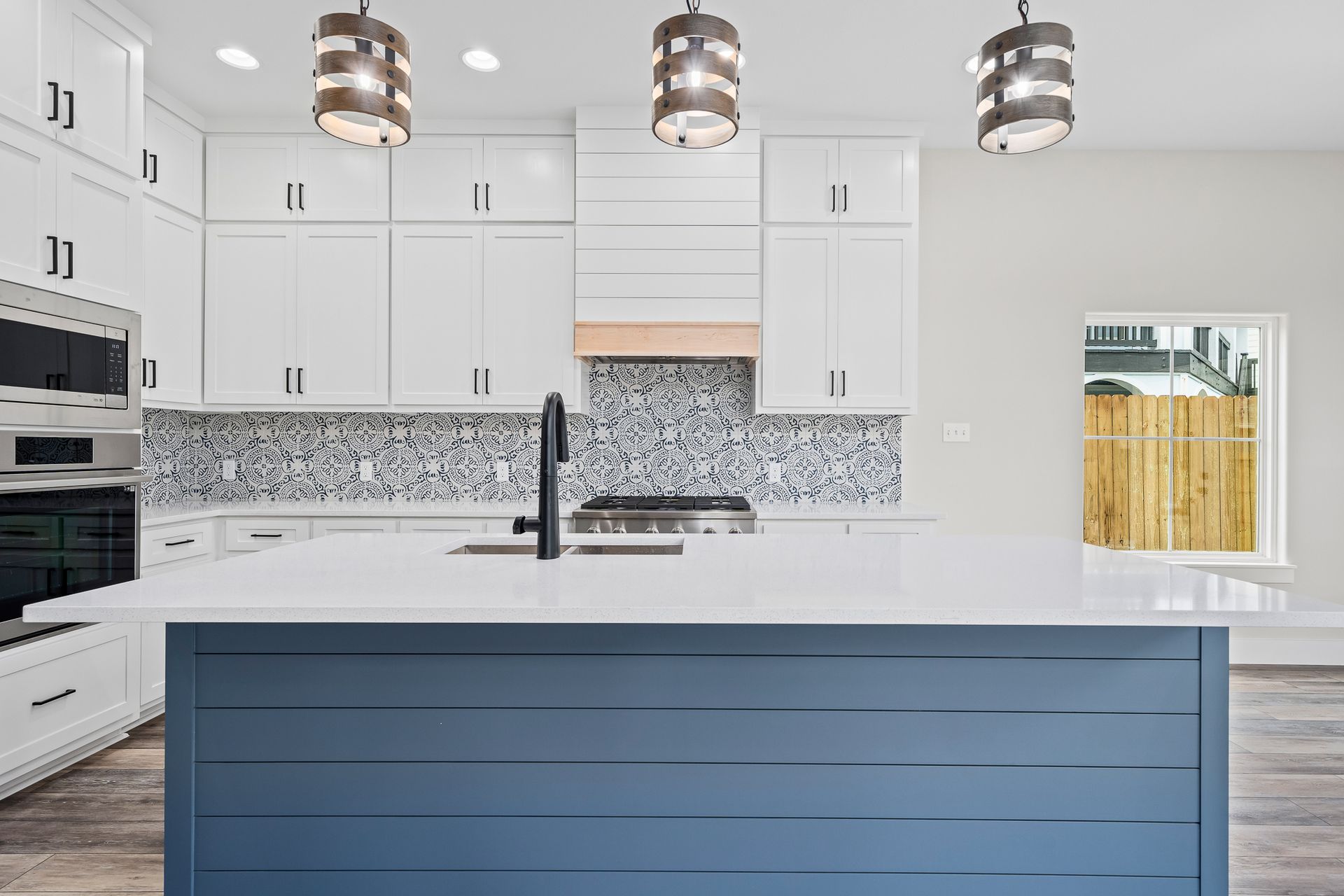 A kitchen with white cabinets and a blue island.