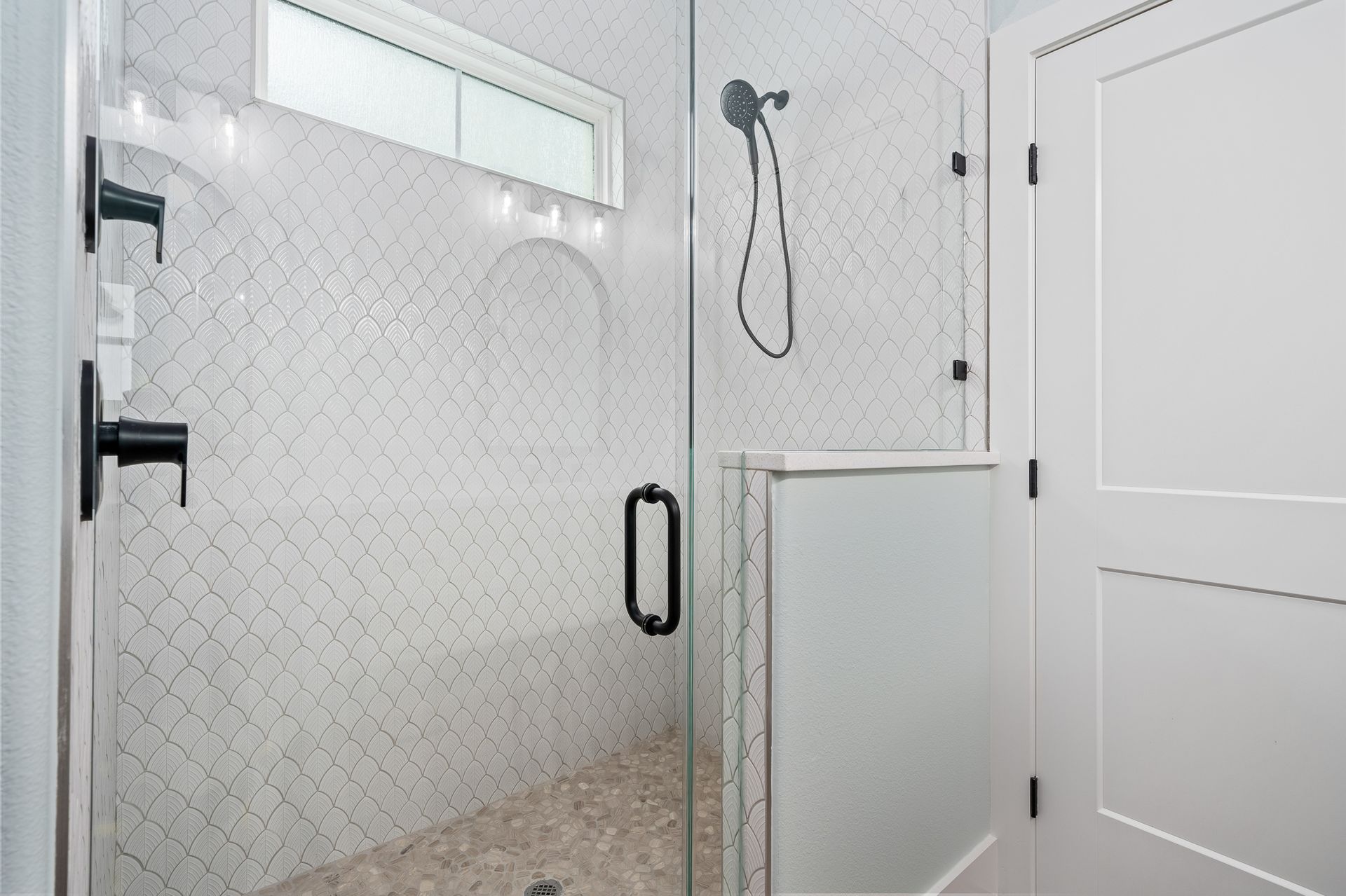 A bathroom with a walk in shower with a glass door.