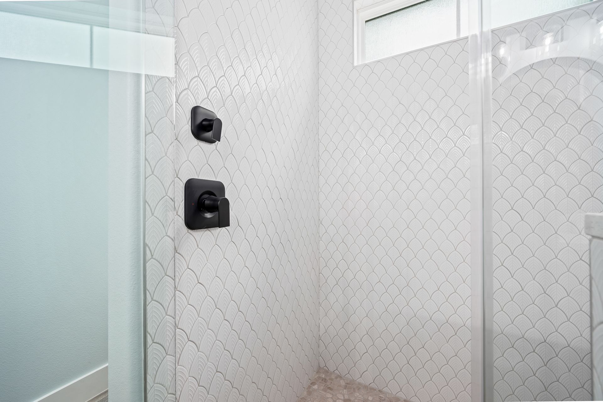 A bathroom with a walk in shower and a window.