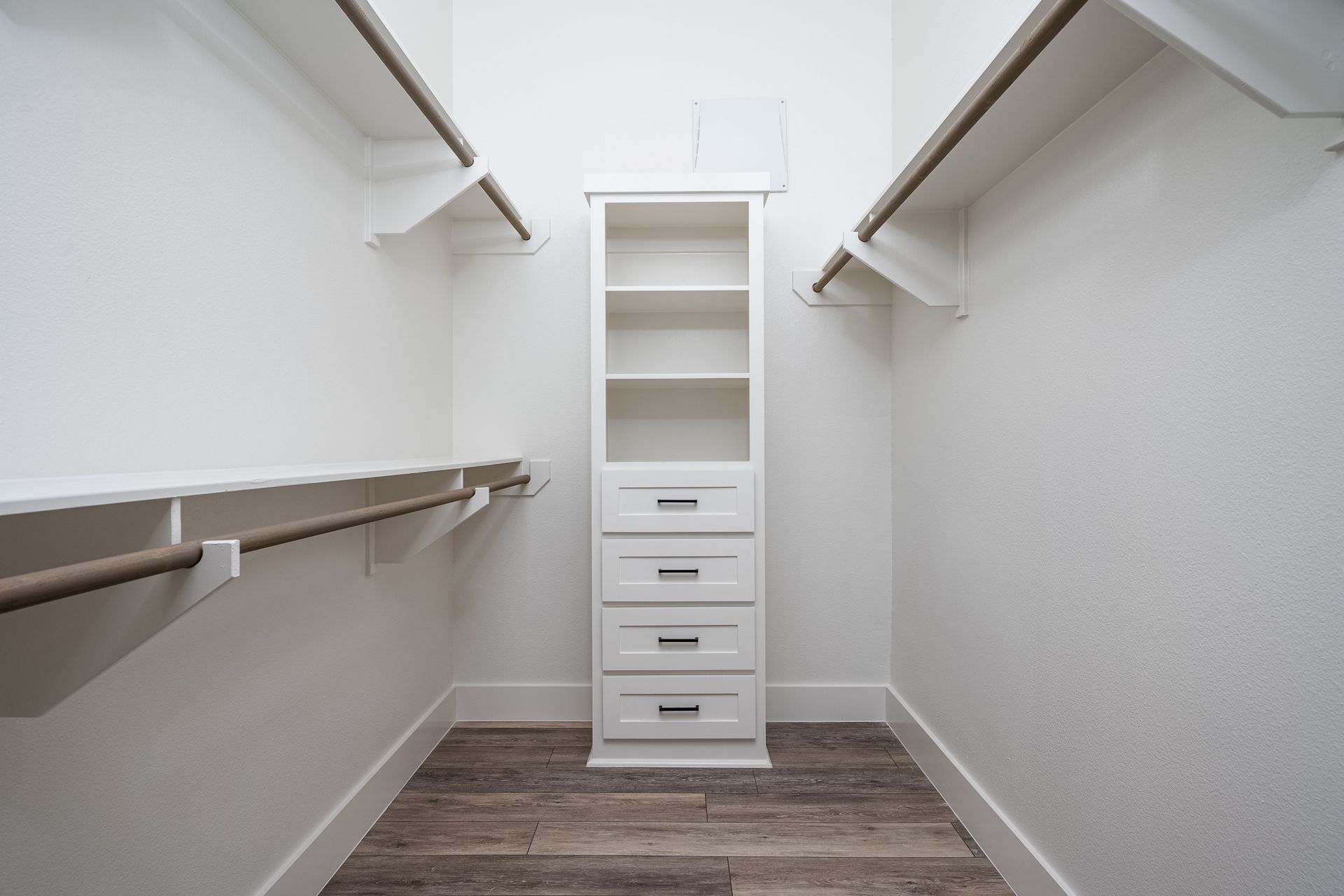 A walk in closet with lots of shelves and drawers.
