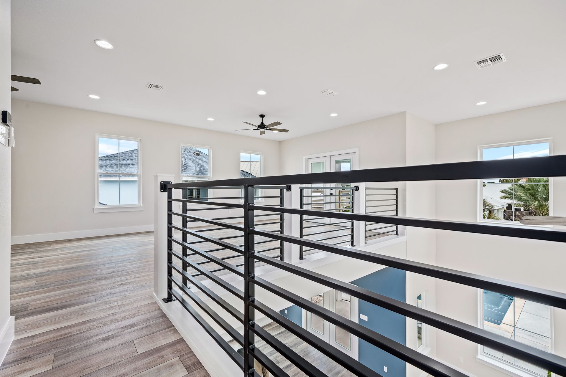 A staircase in a house with a black railing and a ceiling fan.