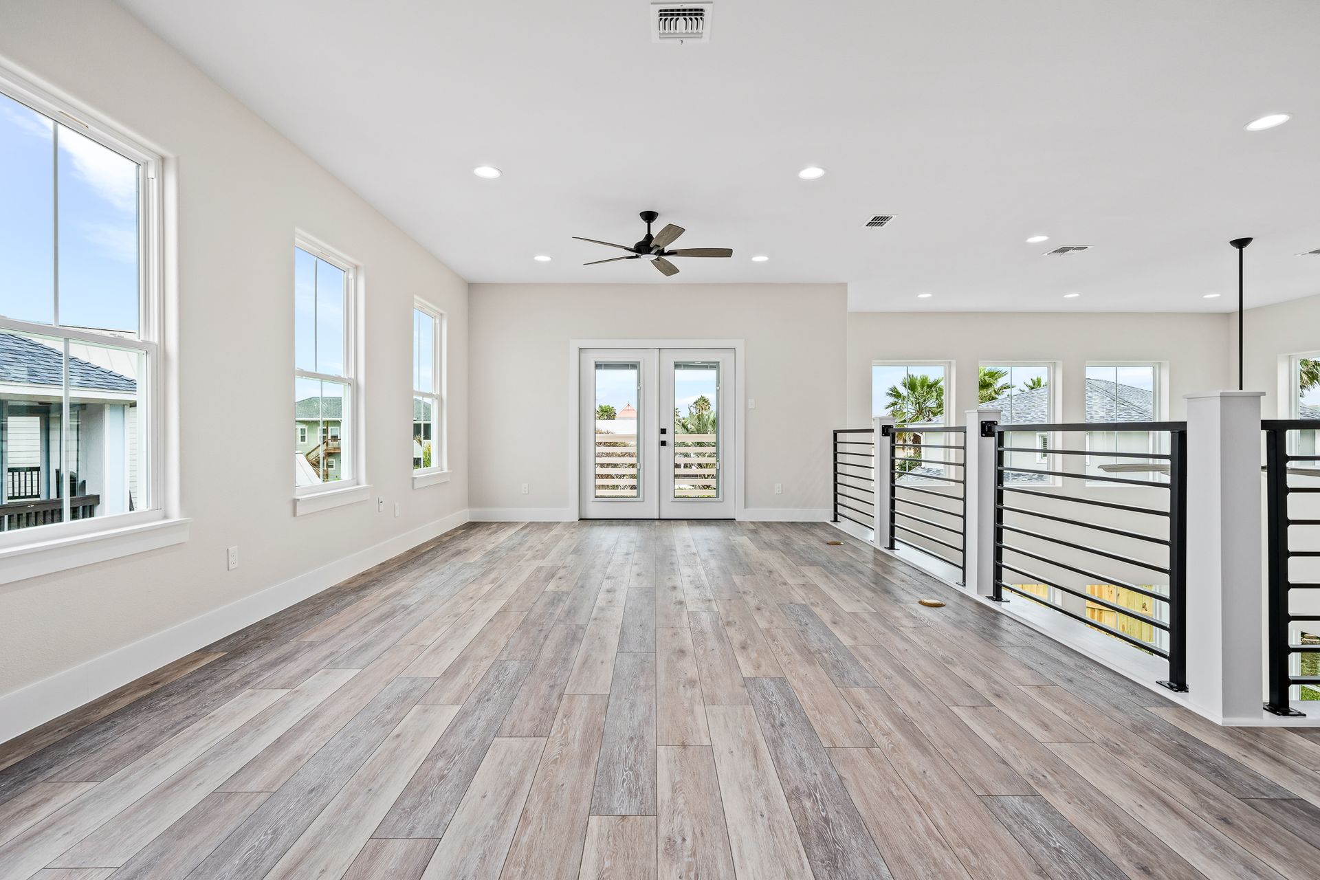A large empty room with hardwood floors and a ceiling fan.