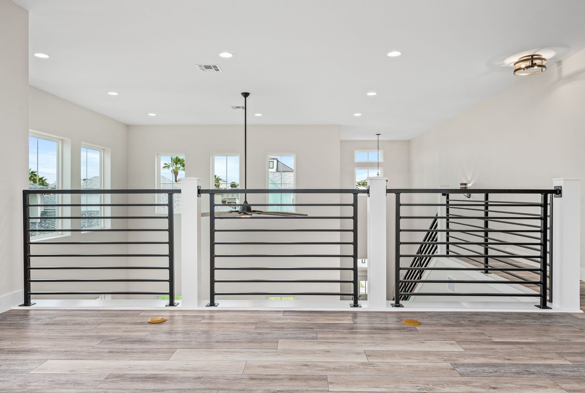 A living room with a black railing and a wooden floor.