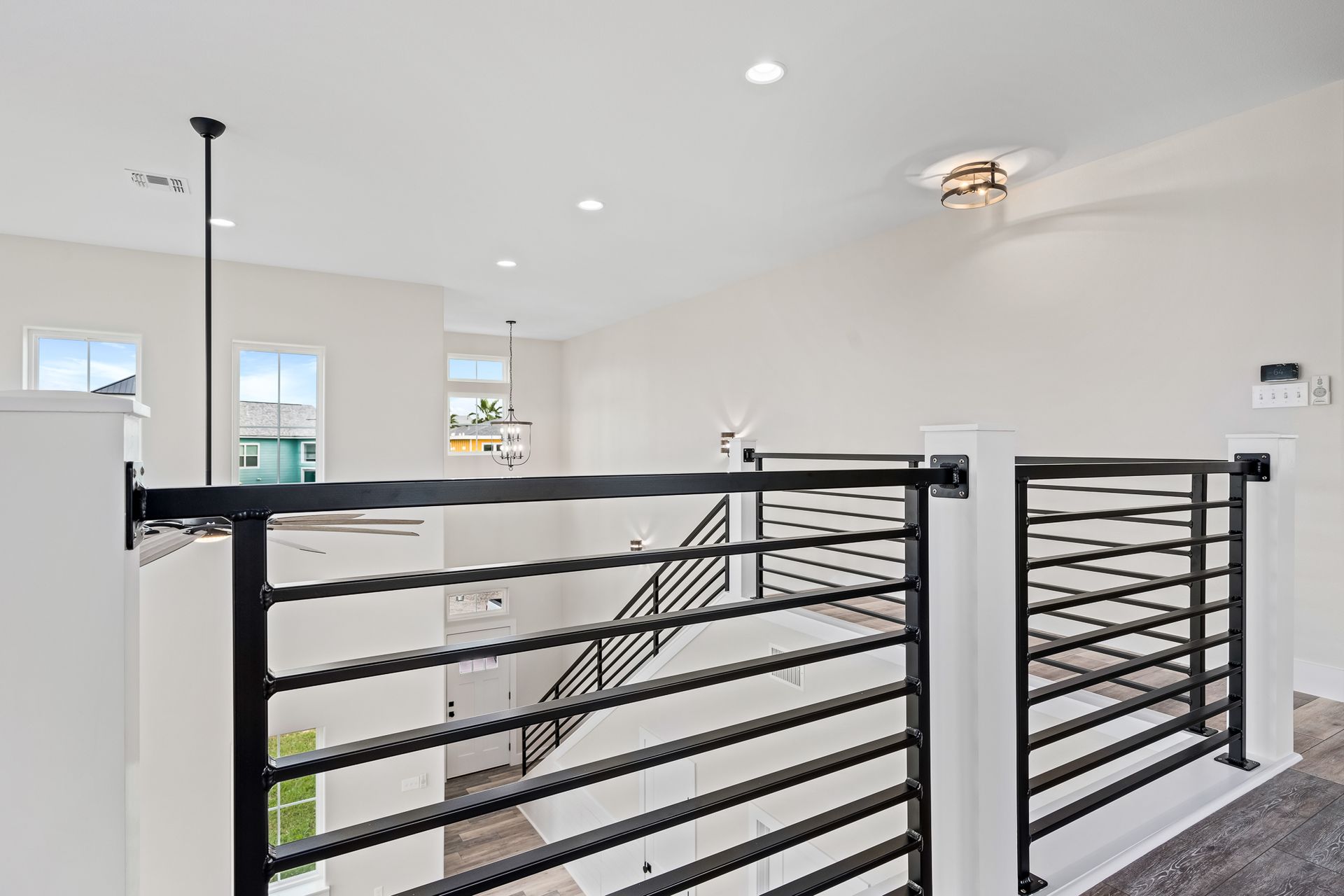 A view of a staircase from the second floor of a house with a black railing.