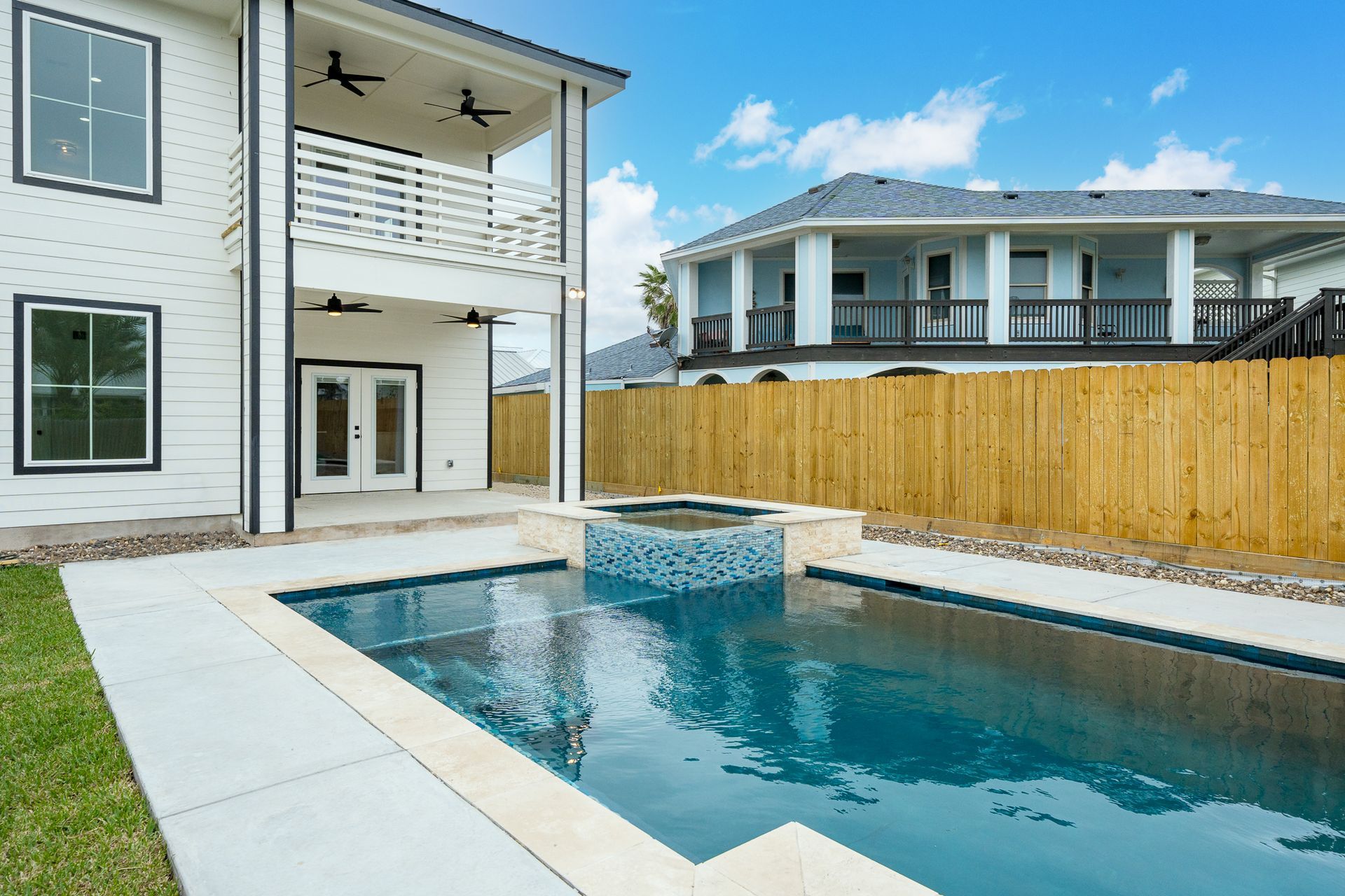 A large swimming pool is in the backyard of a house.
