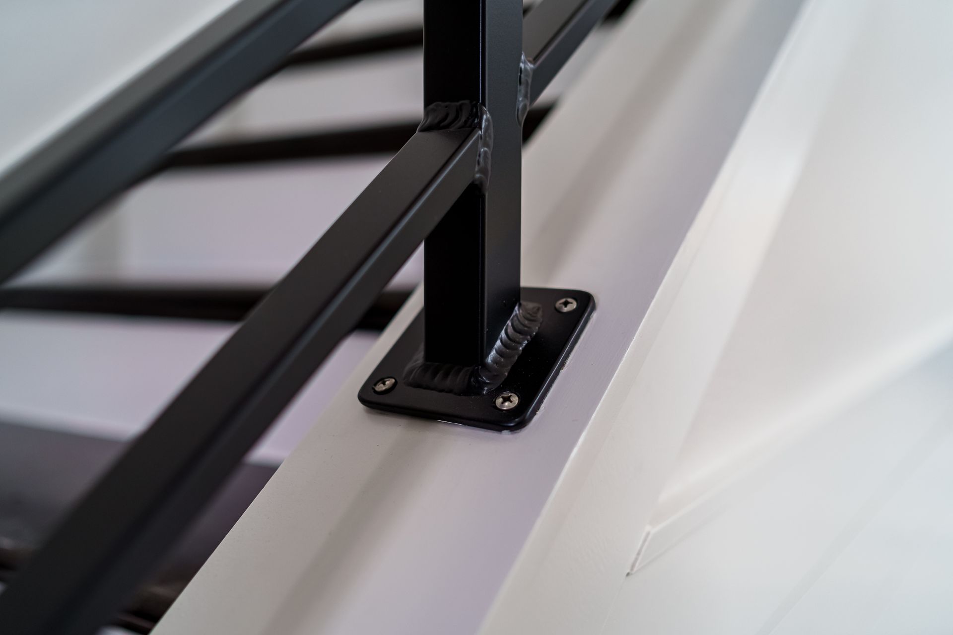 A black metal railing is attached to a white wall.