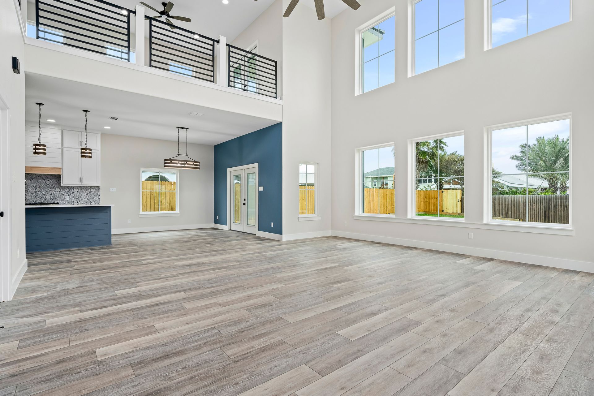 A large empty room with a lot of windows and a ceiling fan.