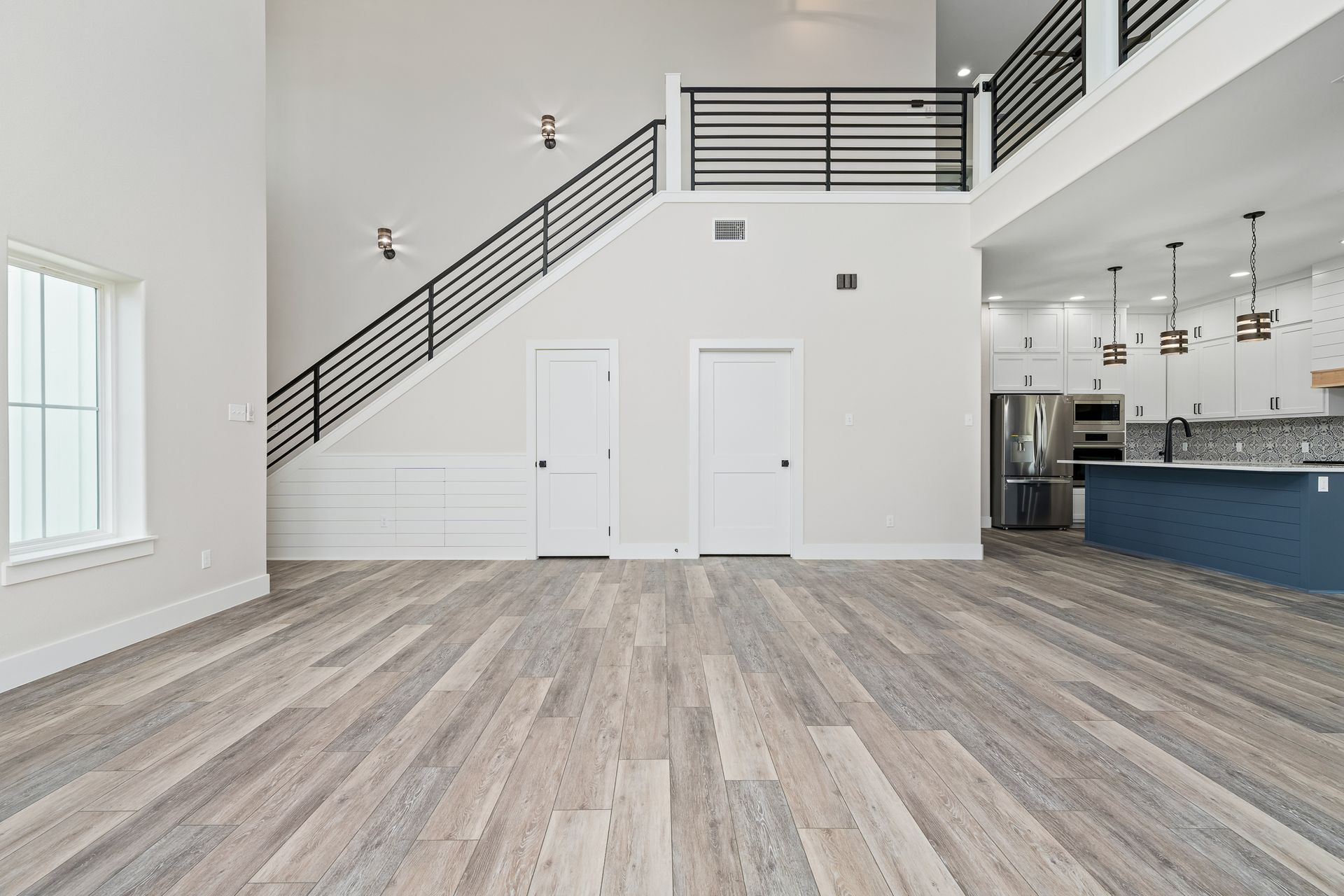 A large empty room with hardwood floors and stairs leading to the second floor.