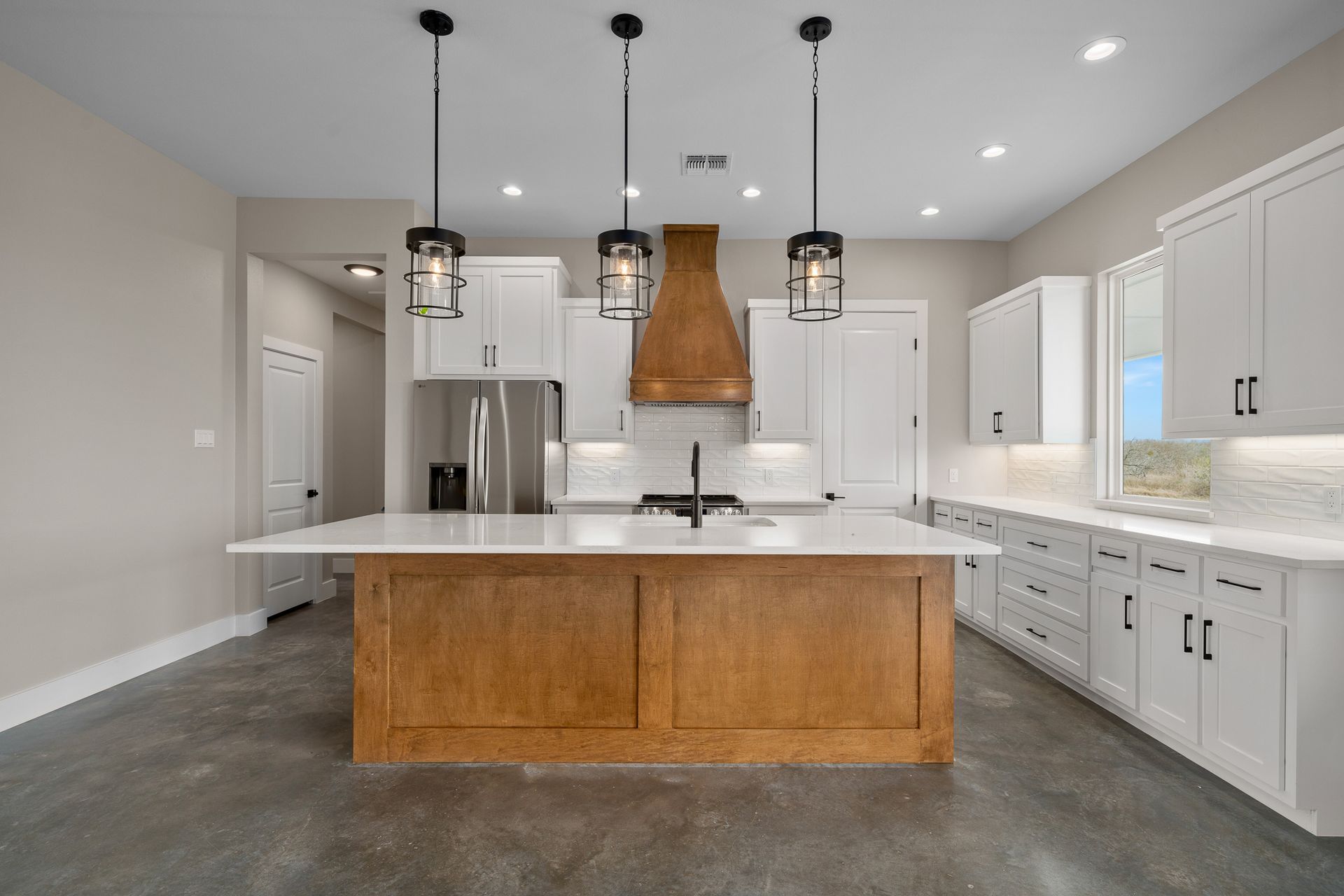 A kitchen with white cabinets and a large island in the middle.