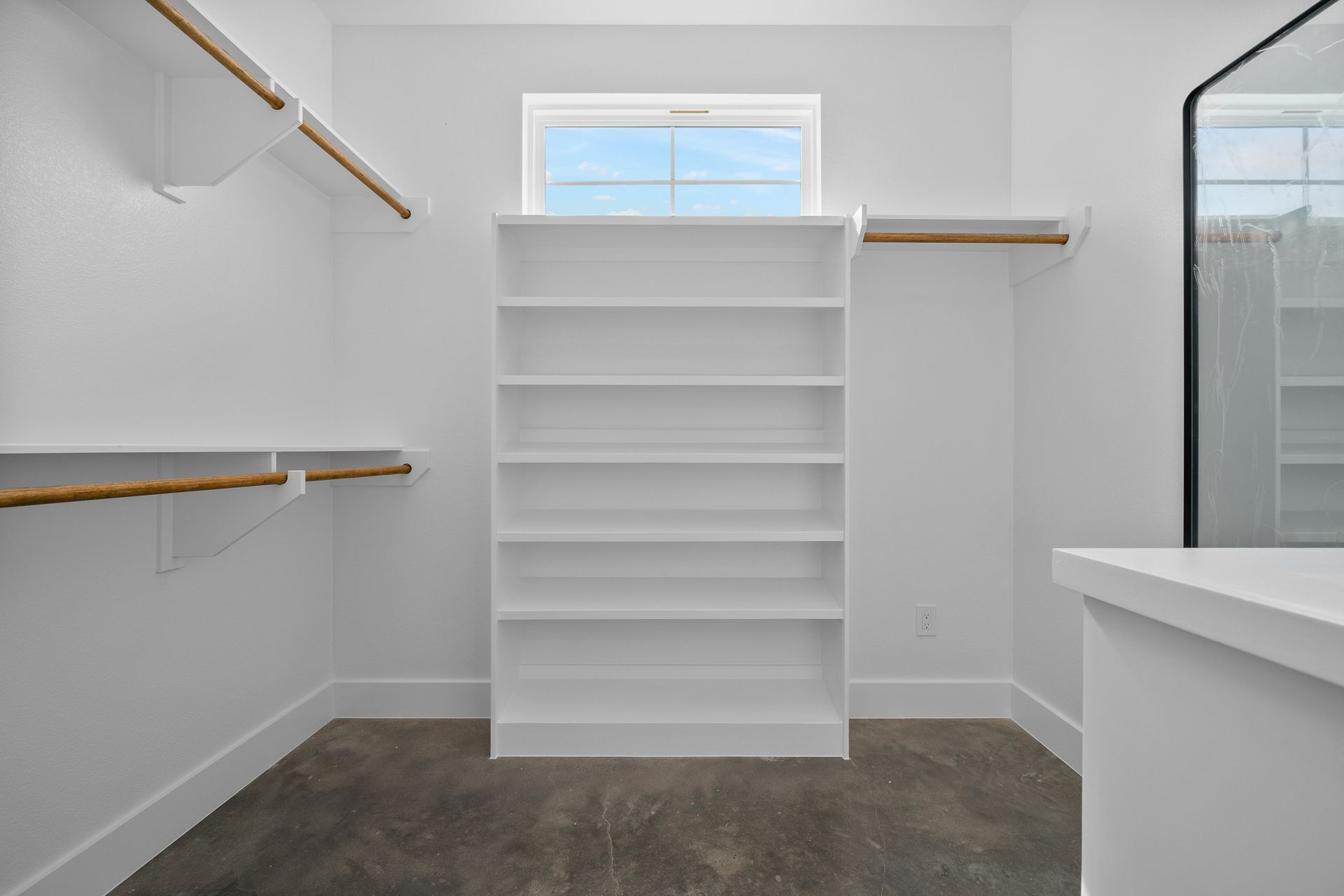 A walk in closet with lots of shelves and a window.