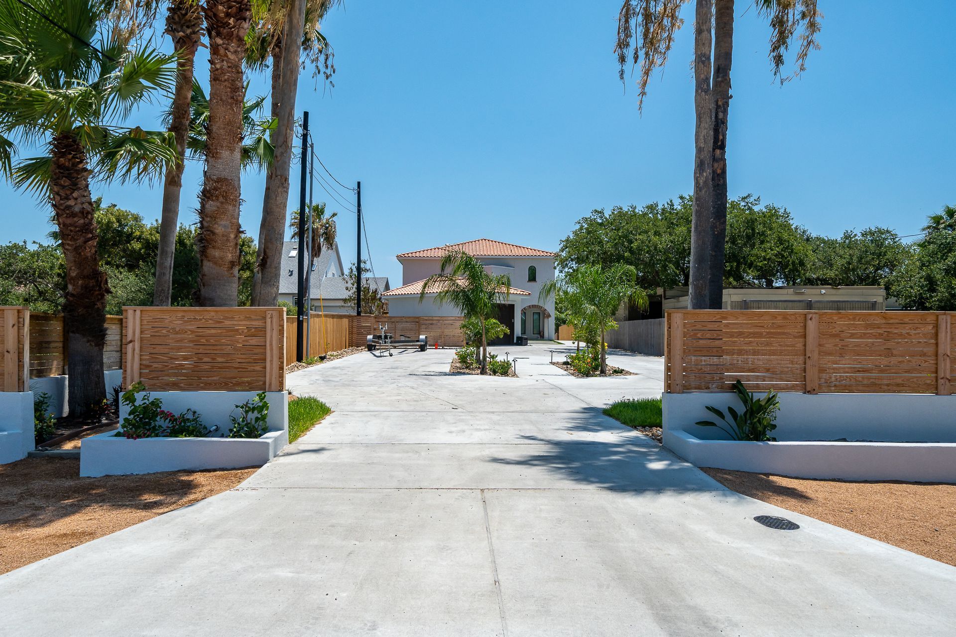 A driveway leading to a house with palm trees on both sides