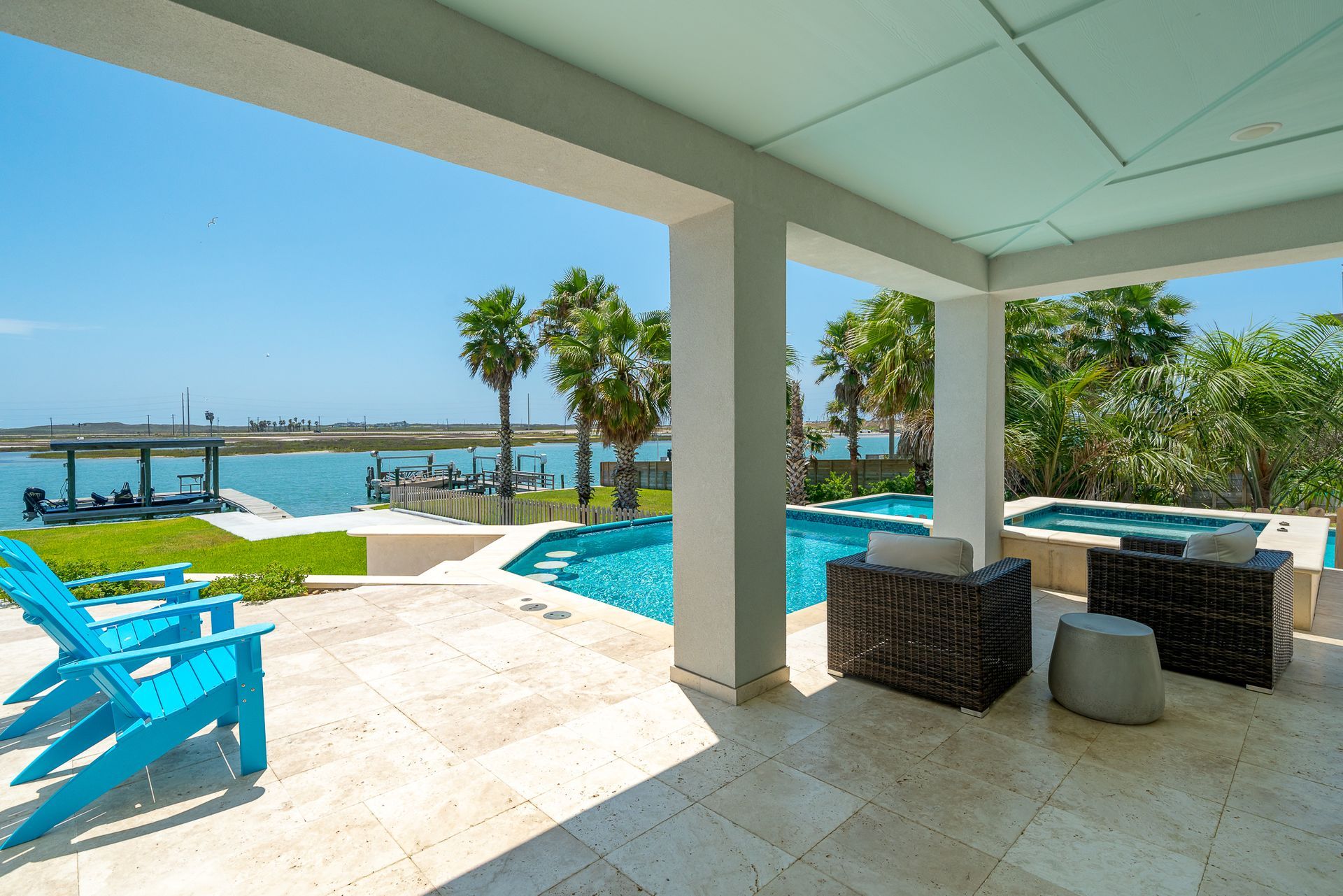 A patio with blue chairs and a pool in the background