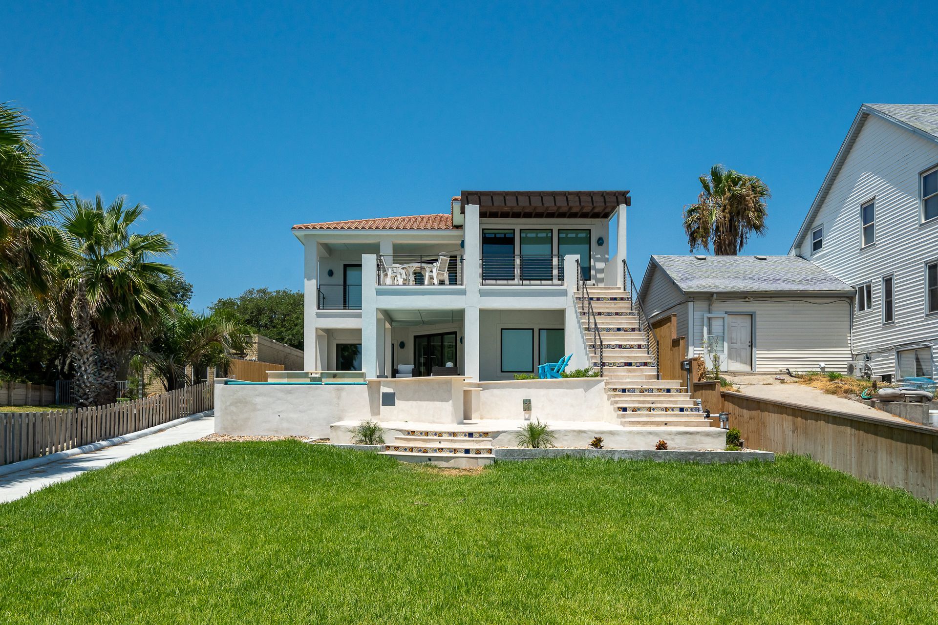 A large white house is sitting on top of a lush green lawn.