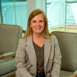 A woman is sitting on a couch in front of a window.