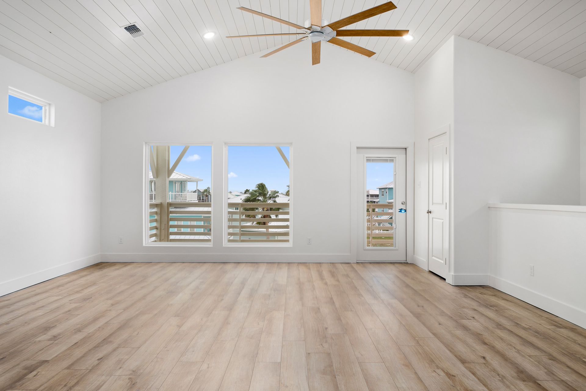 An empty living room with hardwood floors and a ceiling fan.