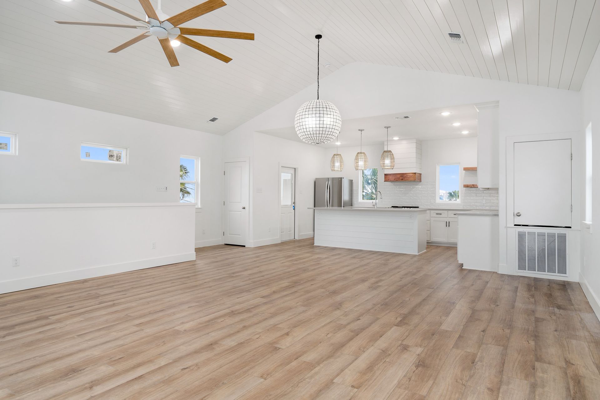 A large empty room with hardwood floors and a ceiling fan.