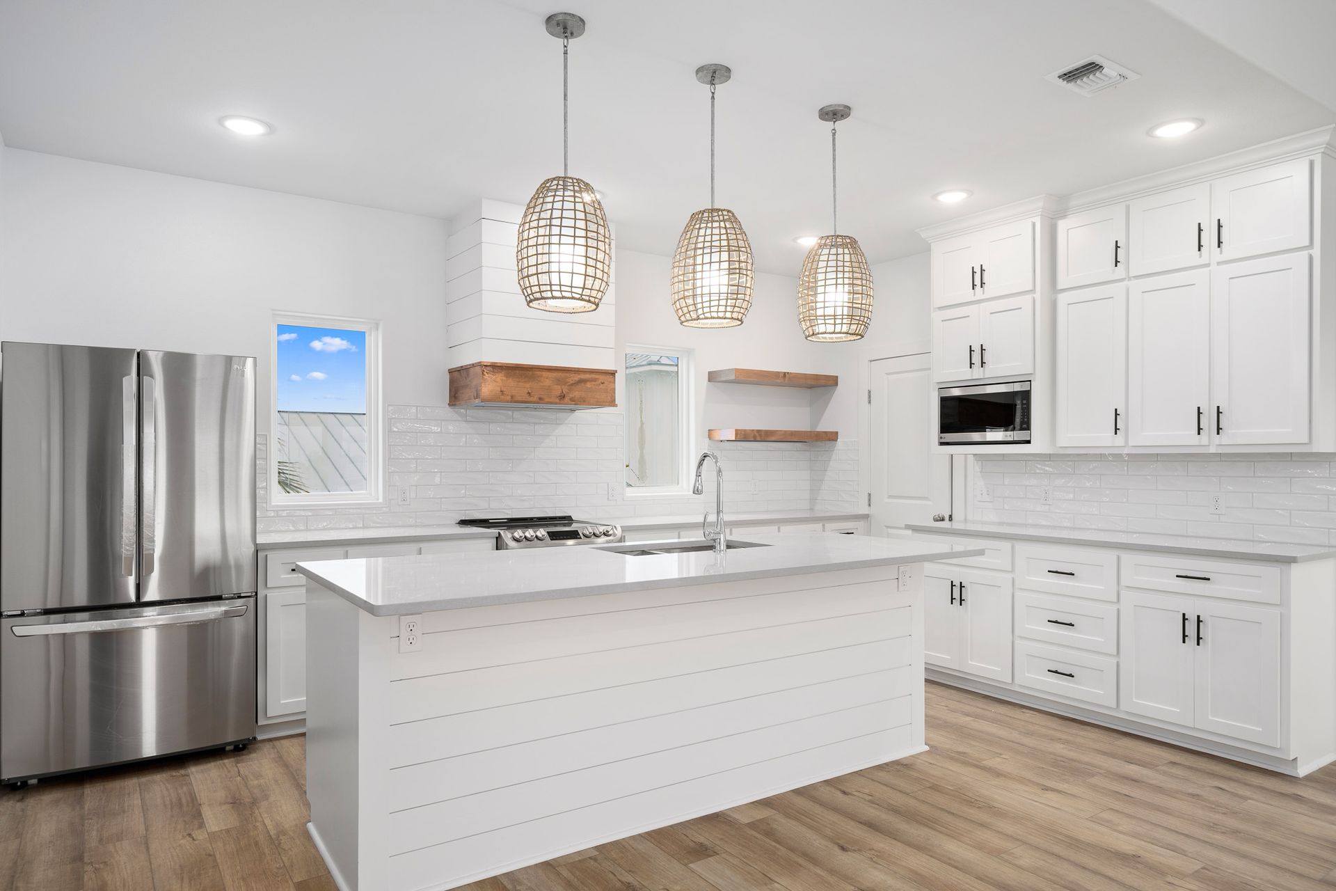A kitchen with white cabinets , stainless steel appliances , and a large island.