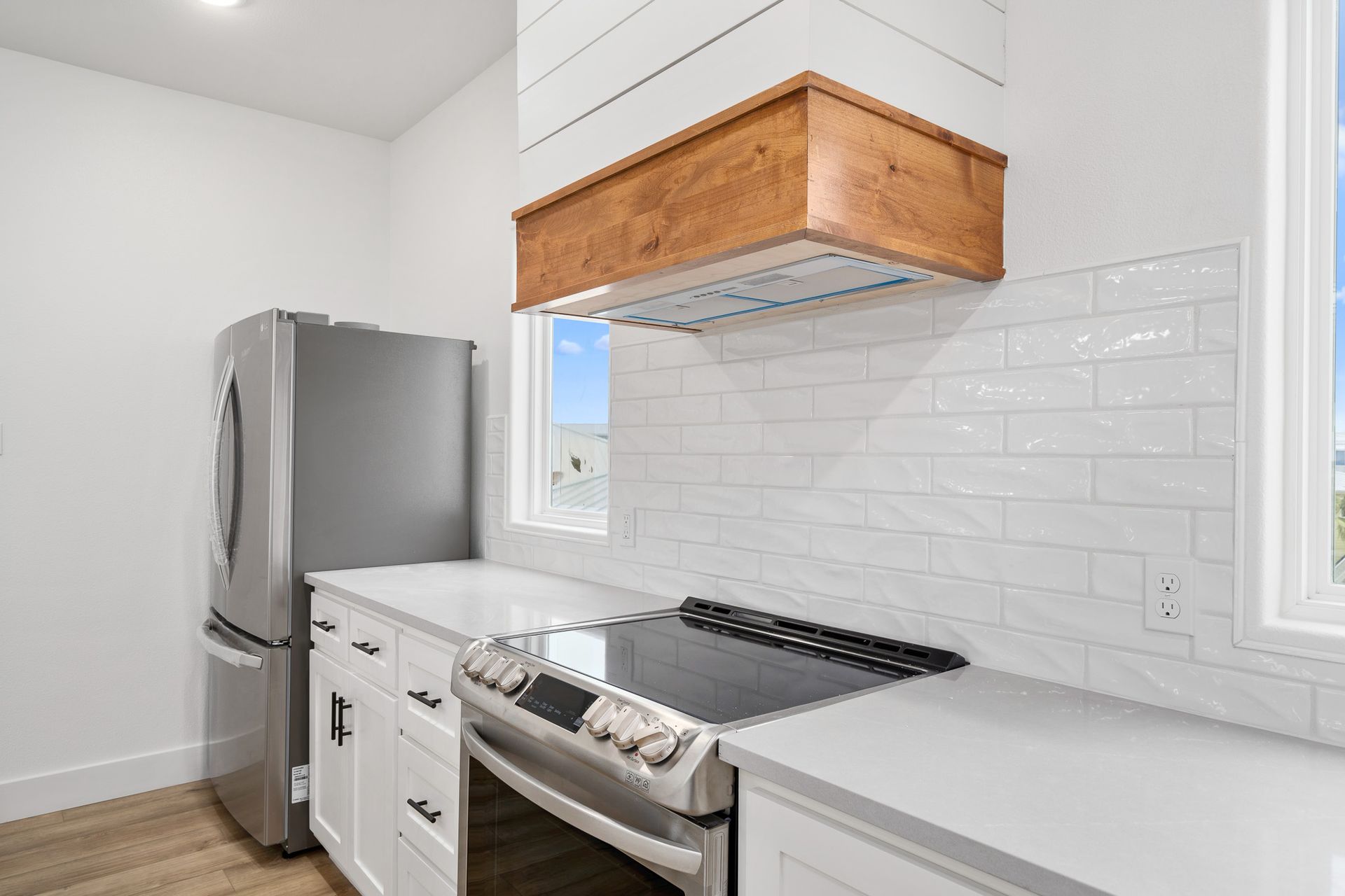 A kitchen with a stove , refrigerator , and hood.
