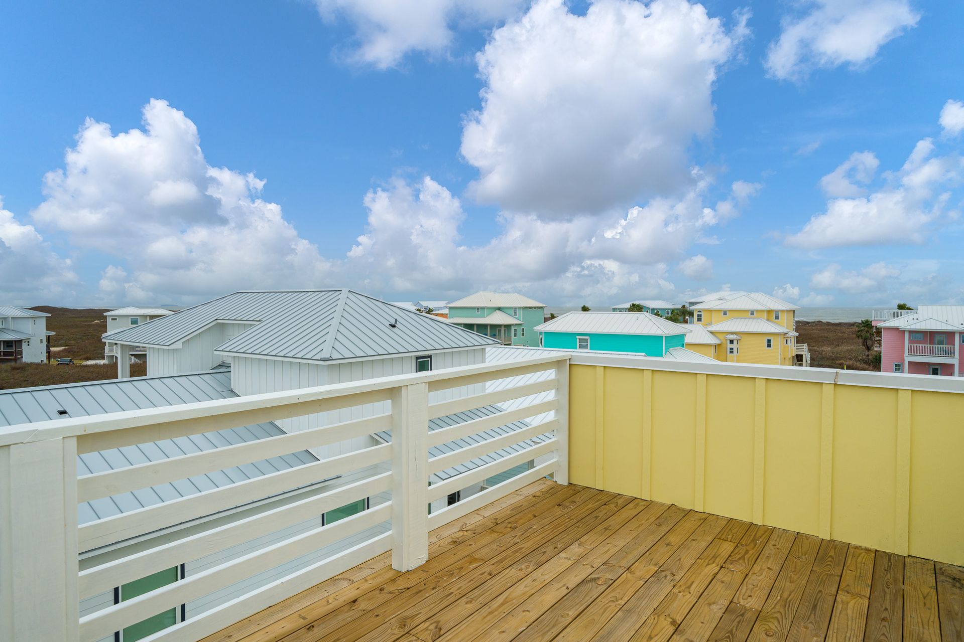 A wooden deck with a white railing and a view of a city.