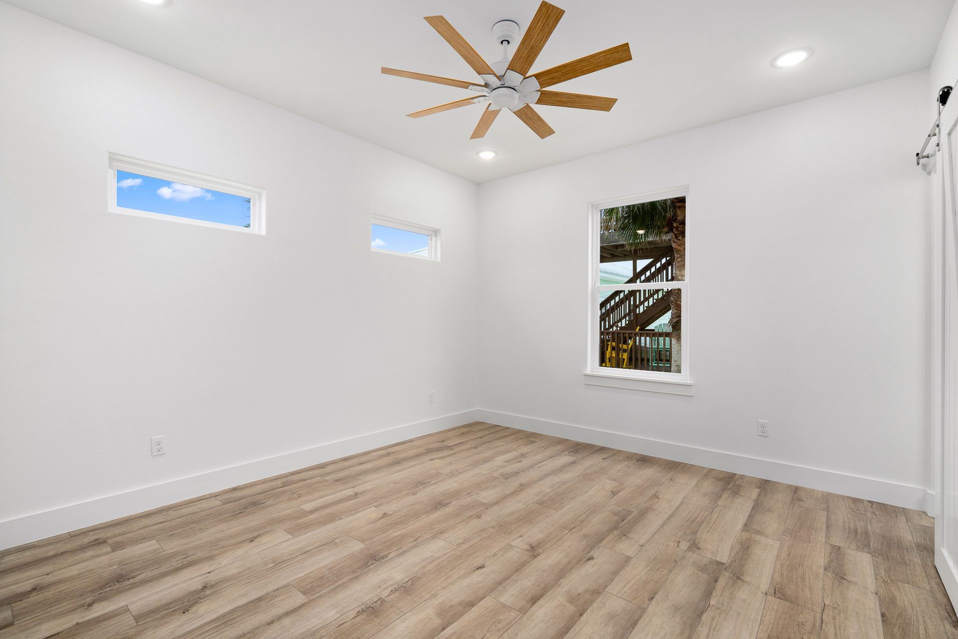 An empty bedroom with hardwood floors and a ceiling fan.