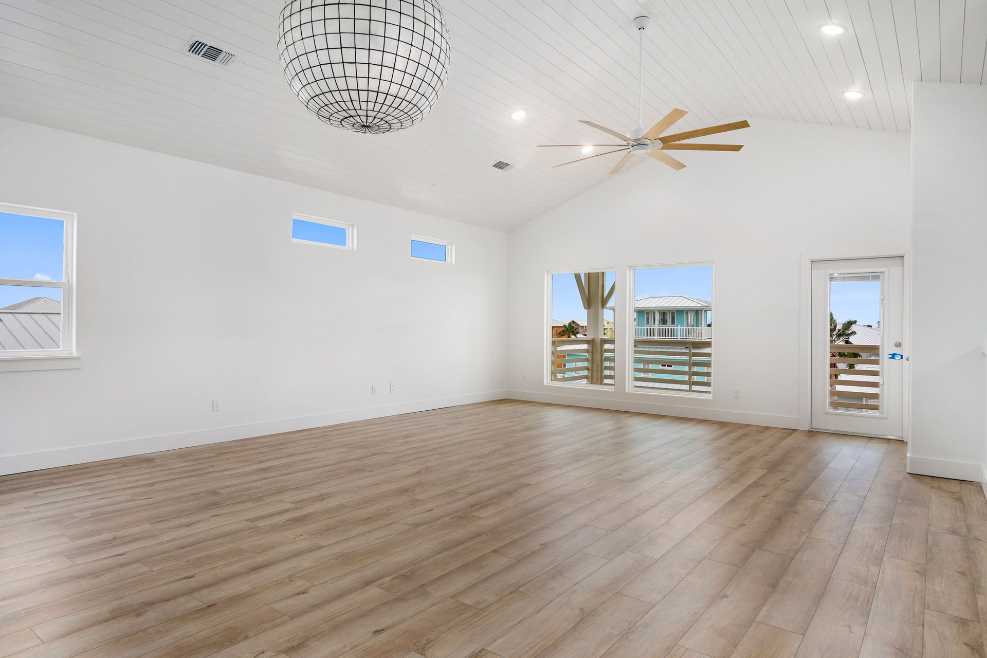 An empty living room with hardwood floors and a ceiling fan.