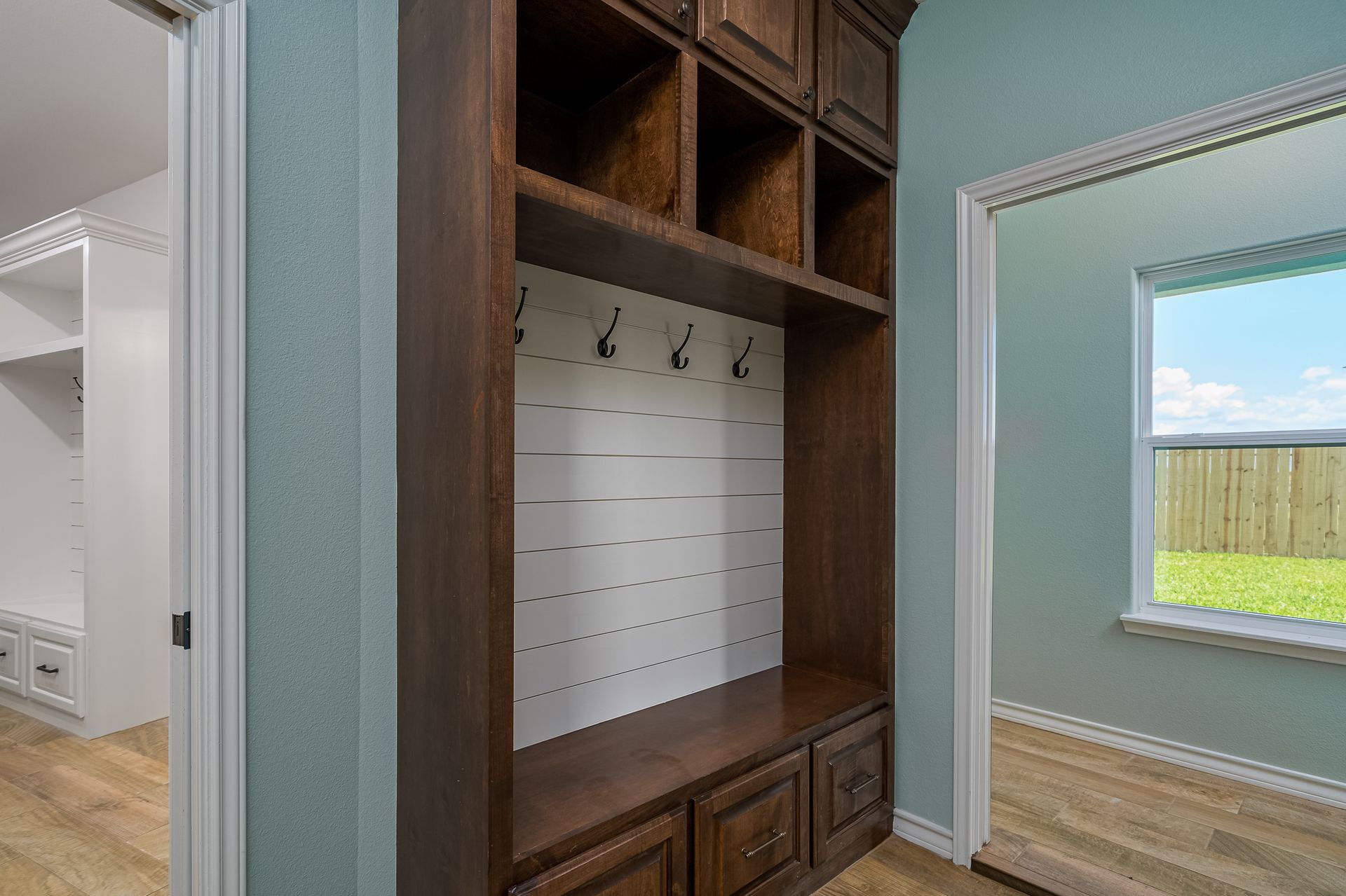 A hallway with a built in coat rack and a window.