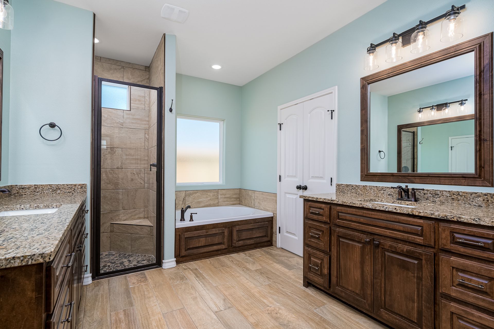 A bathroom with two sinks , a tub and a shower.