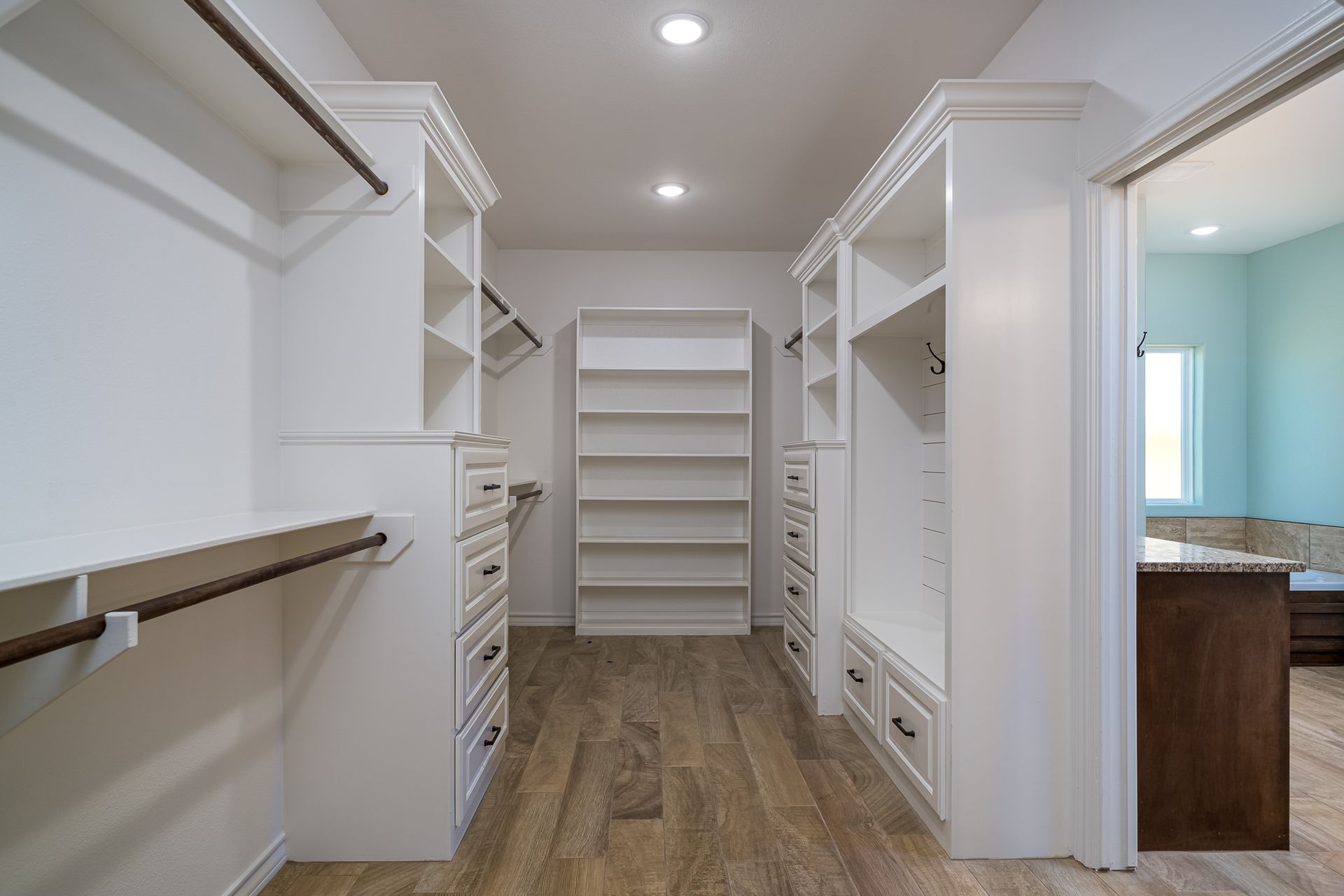 A walk in closet with lots of shelves and drawers in a house.