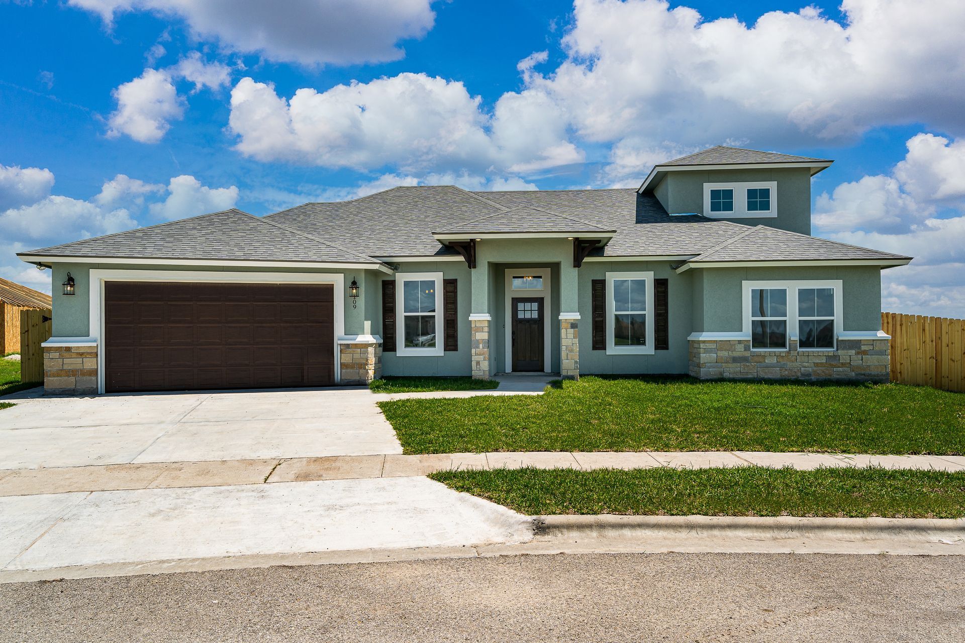 A large house with a large garage and a fence in front of it