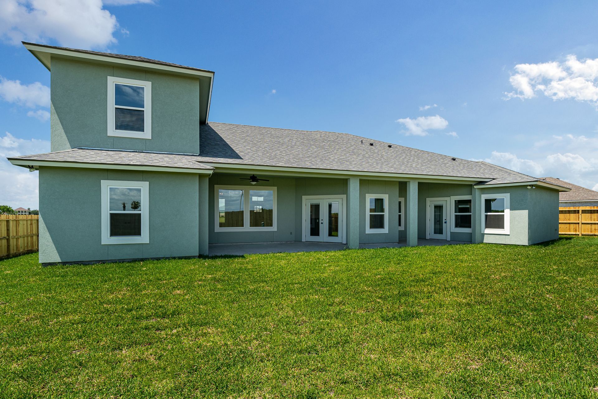 A large house with a lot of windows is sitting on top of a lush green field.
