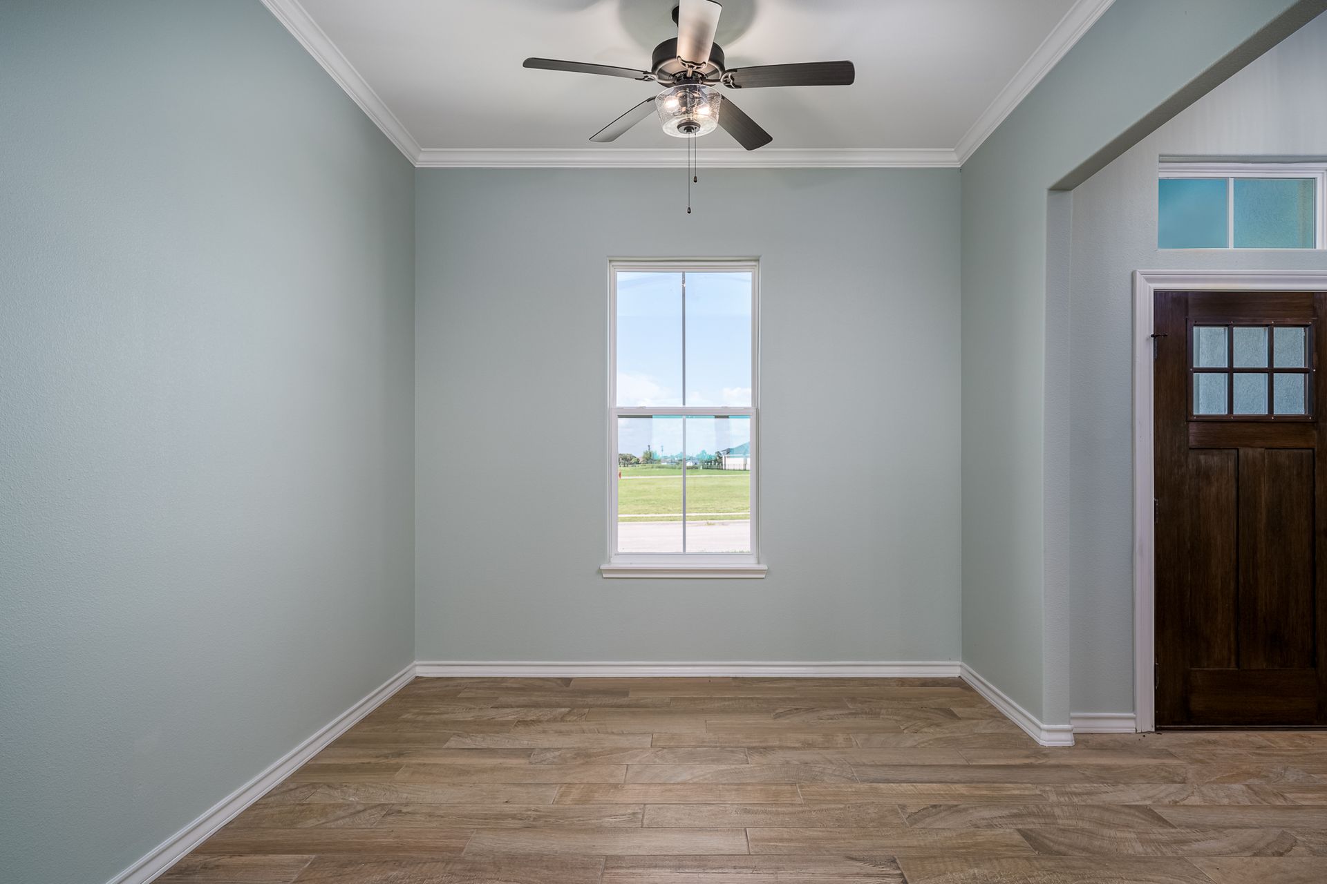 An empty room with a ceiling fan and a window.