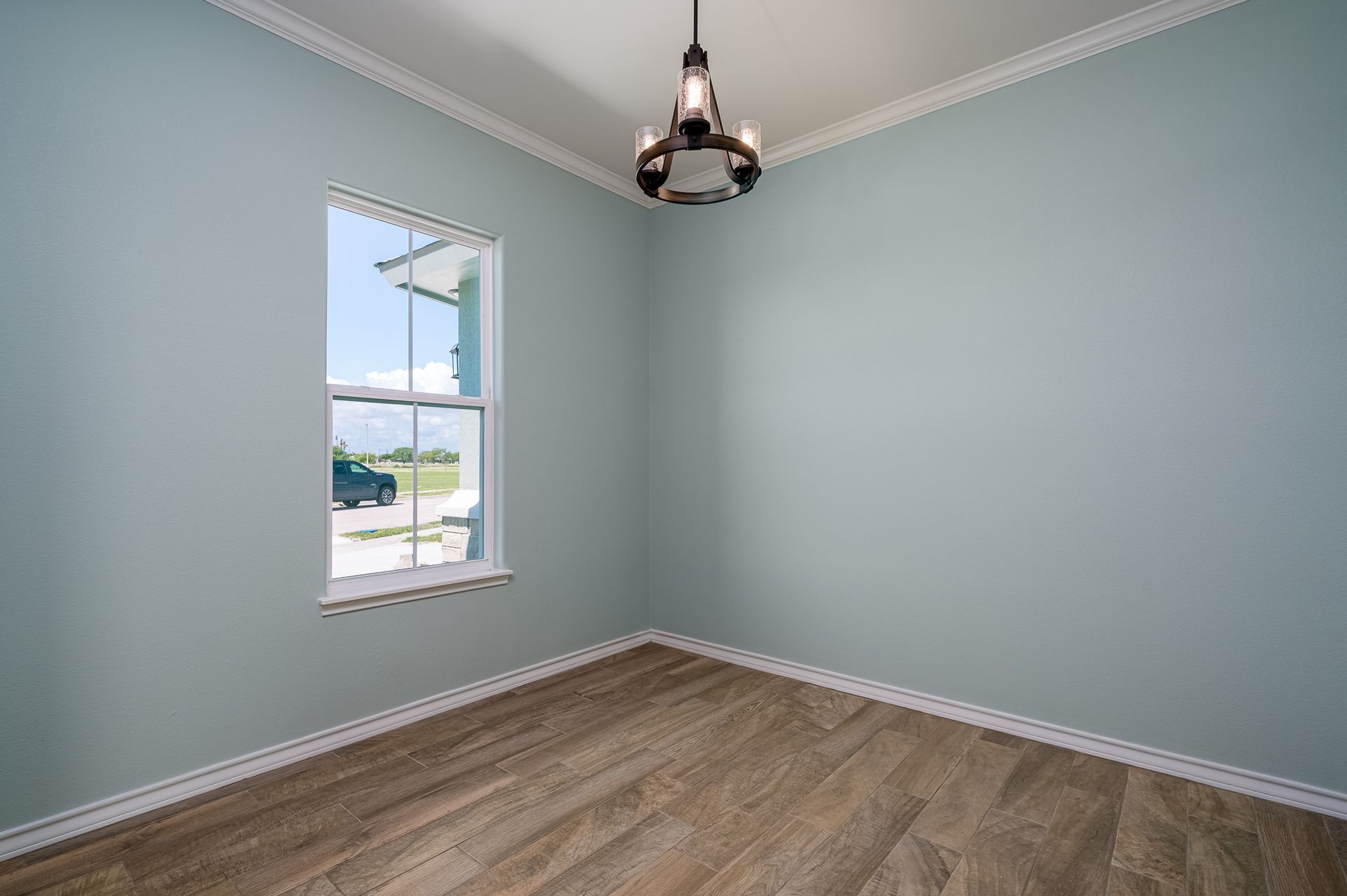 An empty room with a window and a chandelier.