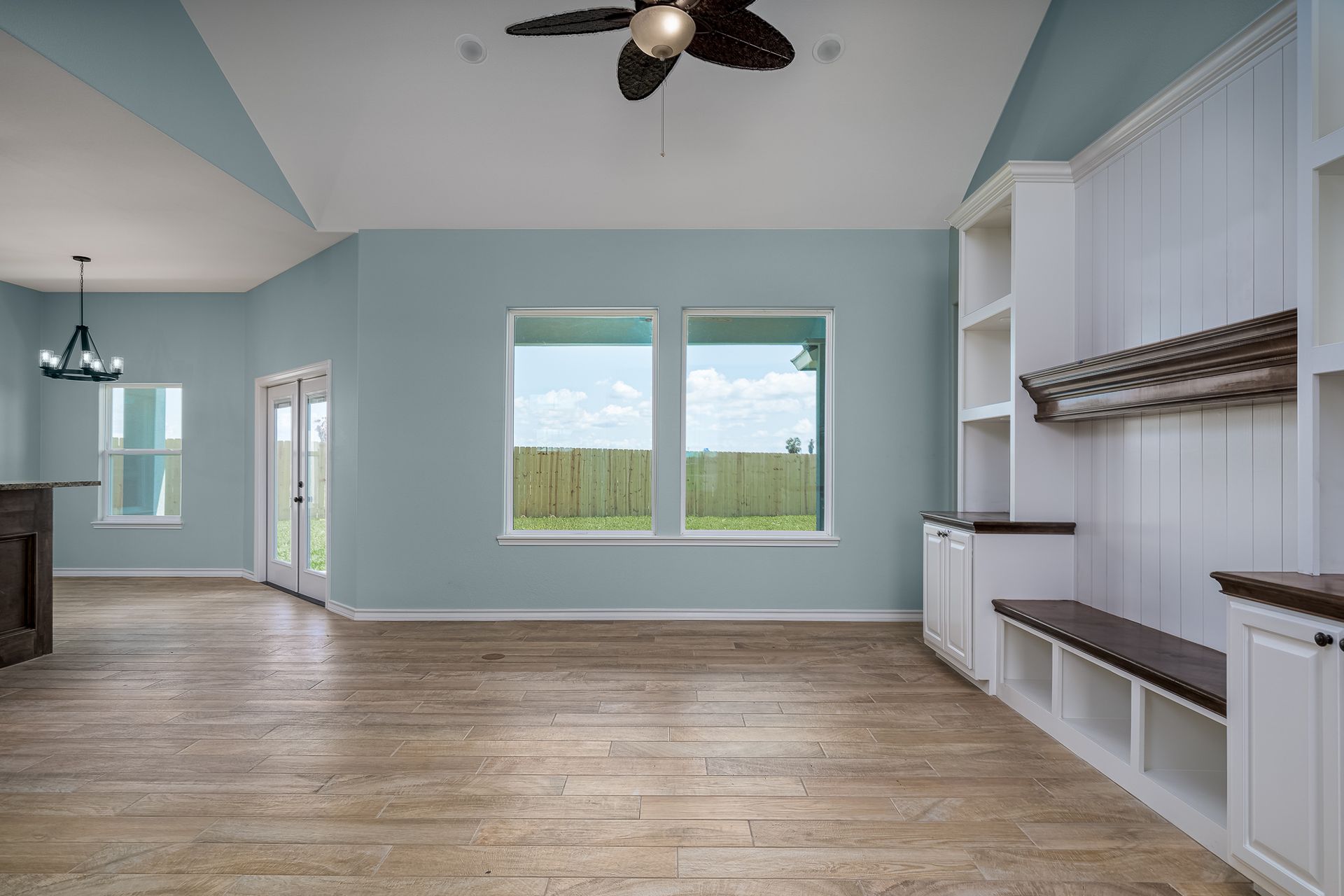 An empty living room with hardwood floors and a ceiling fan.